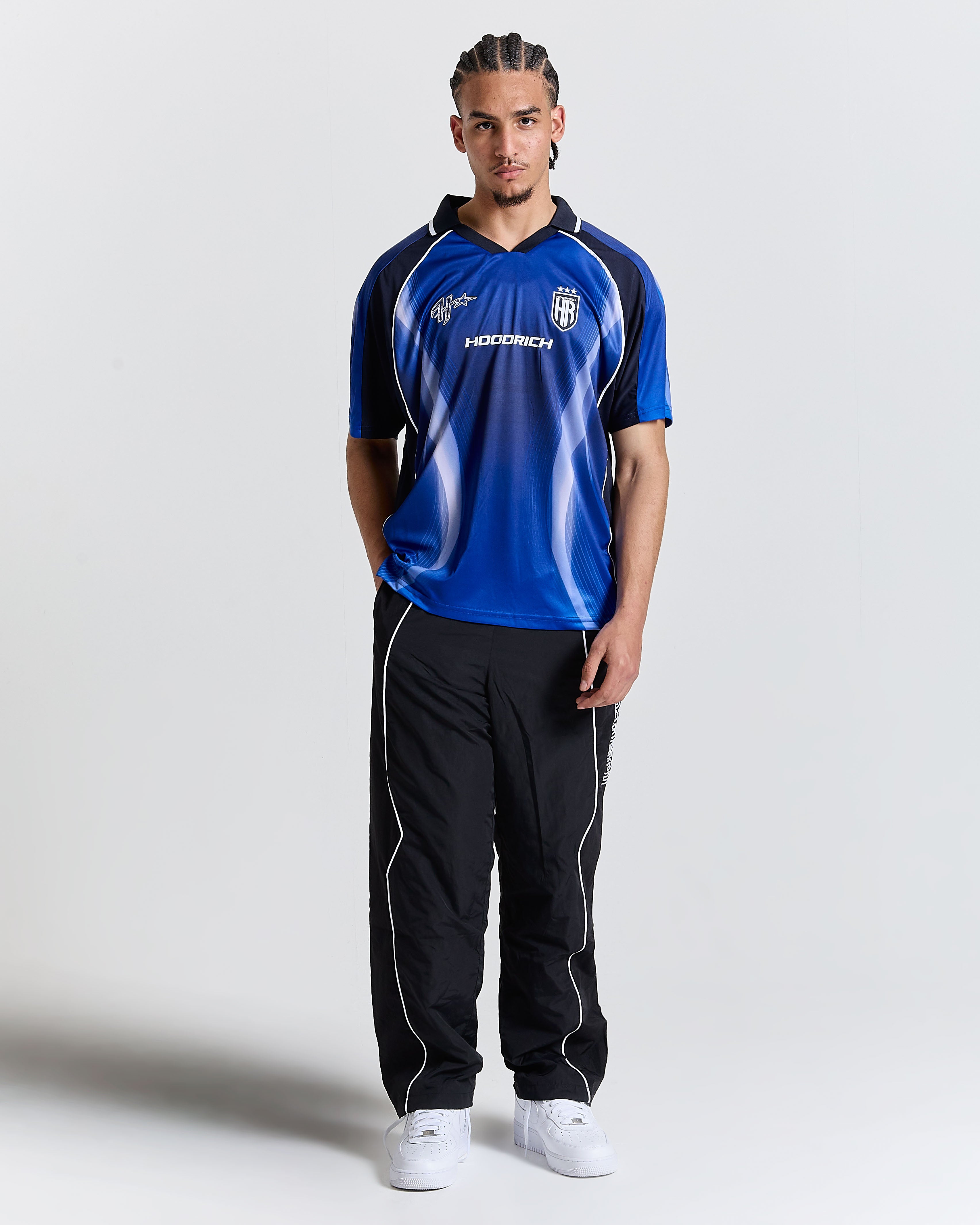 Person wearing a blue sports jersey with black accents and black pants on a white background