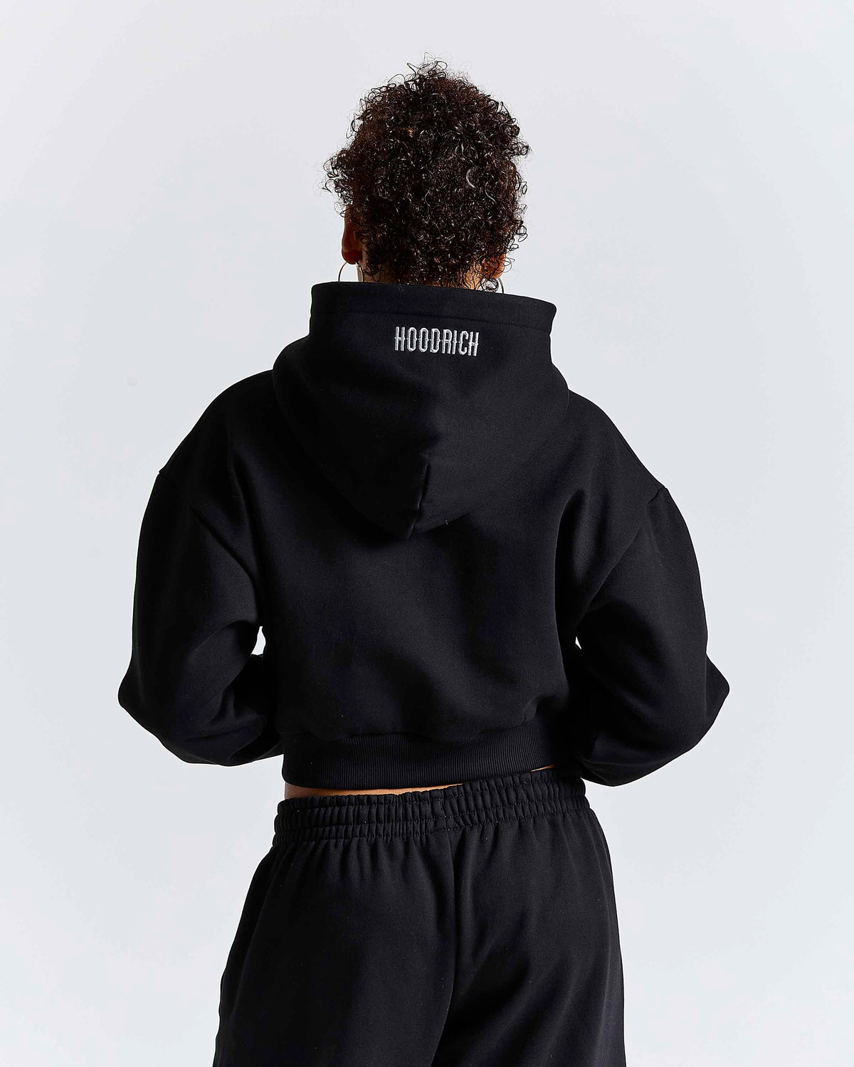 Displays a model wearing the Black 'Hoodrich' branded women's Solace Full Tracksuit