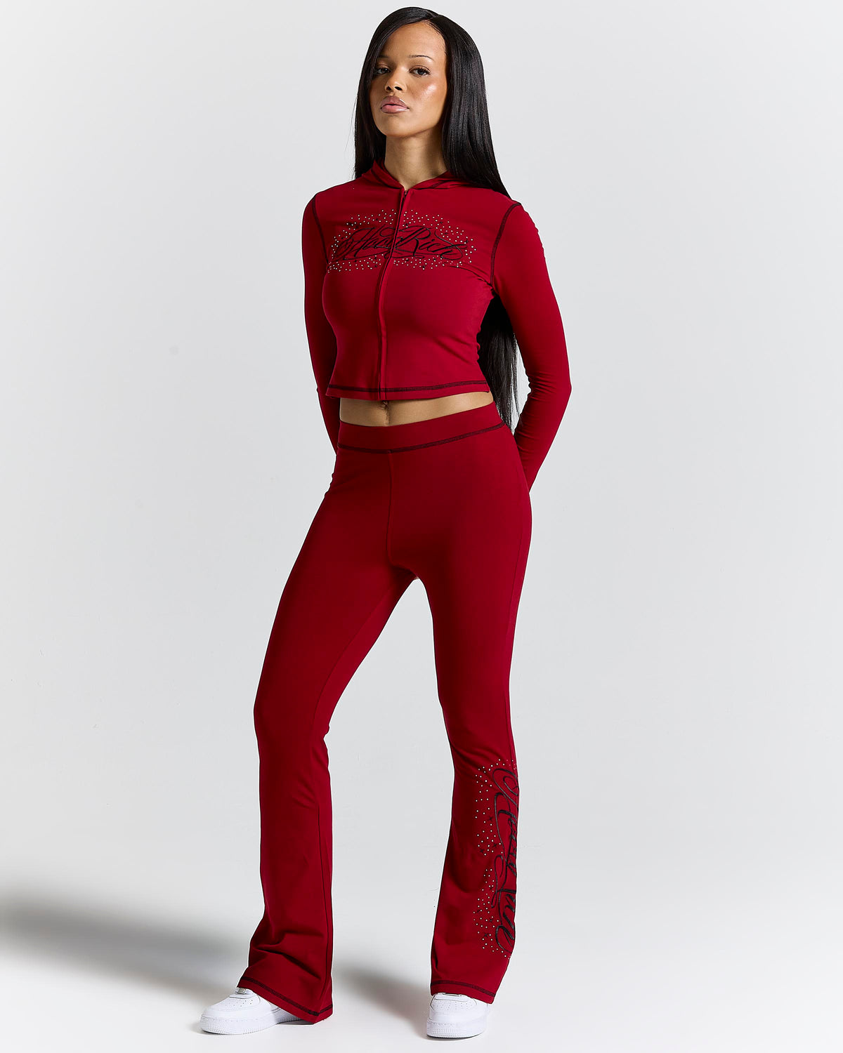 Displays a model wearing the Red 'Hoodrich' branded women's Gleam Full Tracksuit