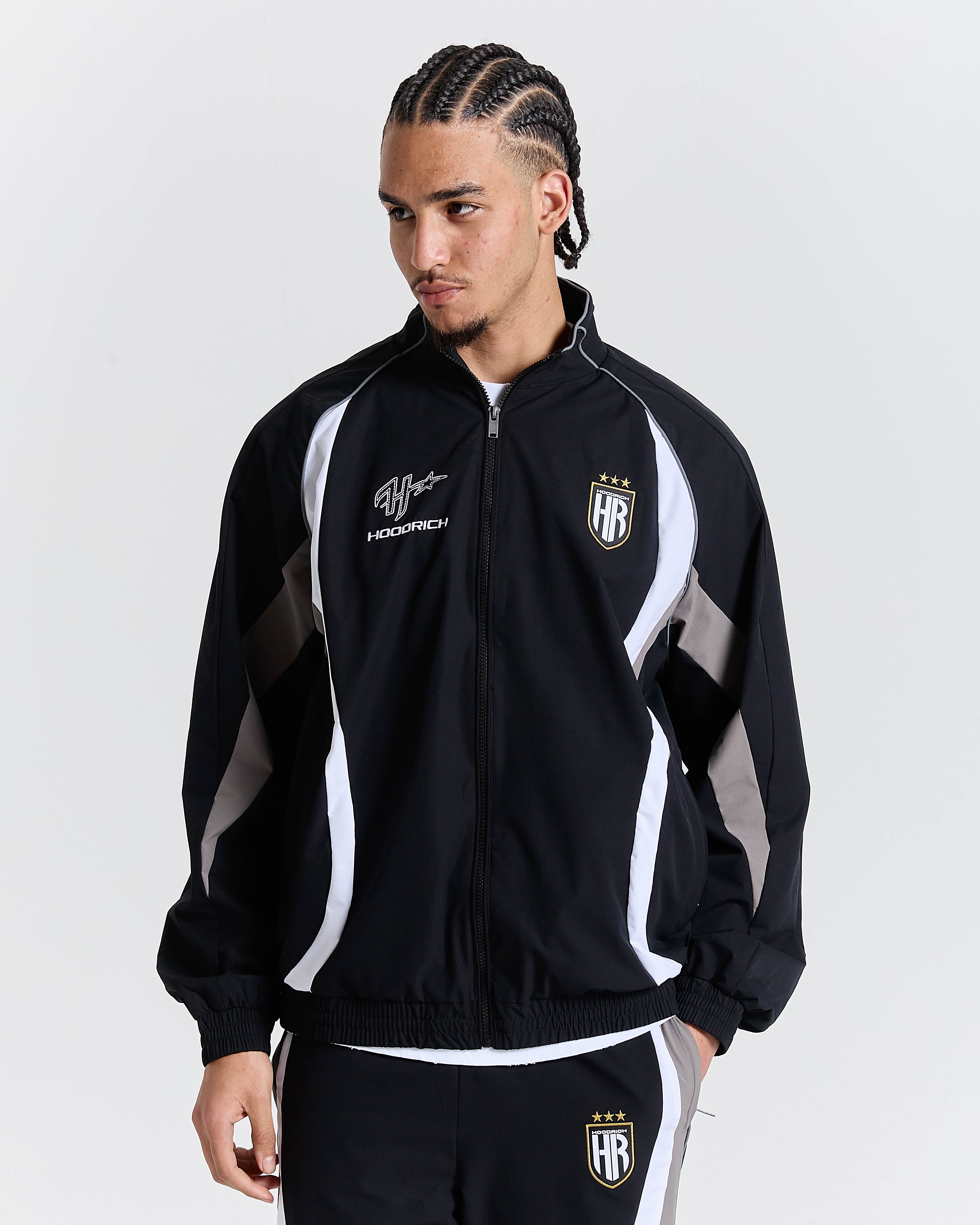 Person wearing a black and white tracksuit with visible branding on a plain background