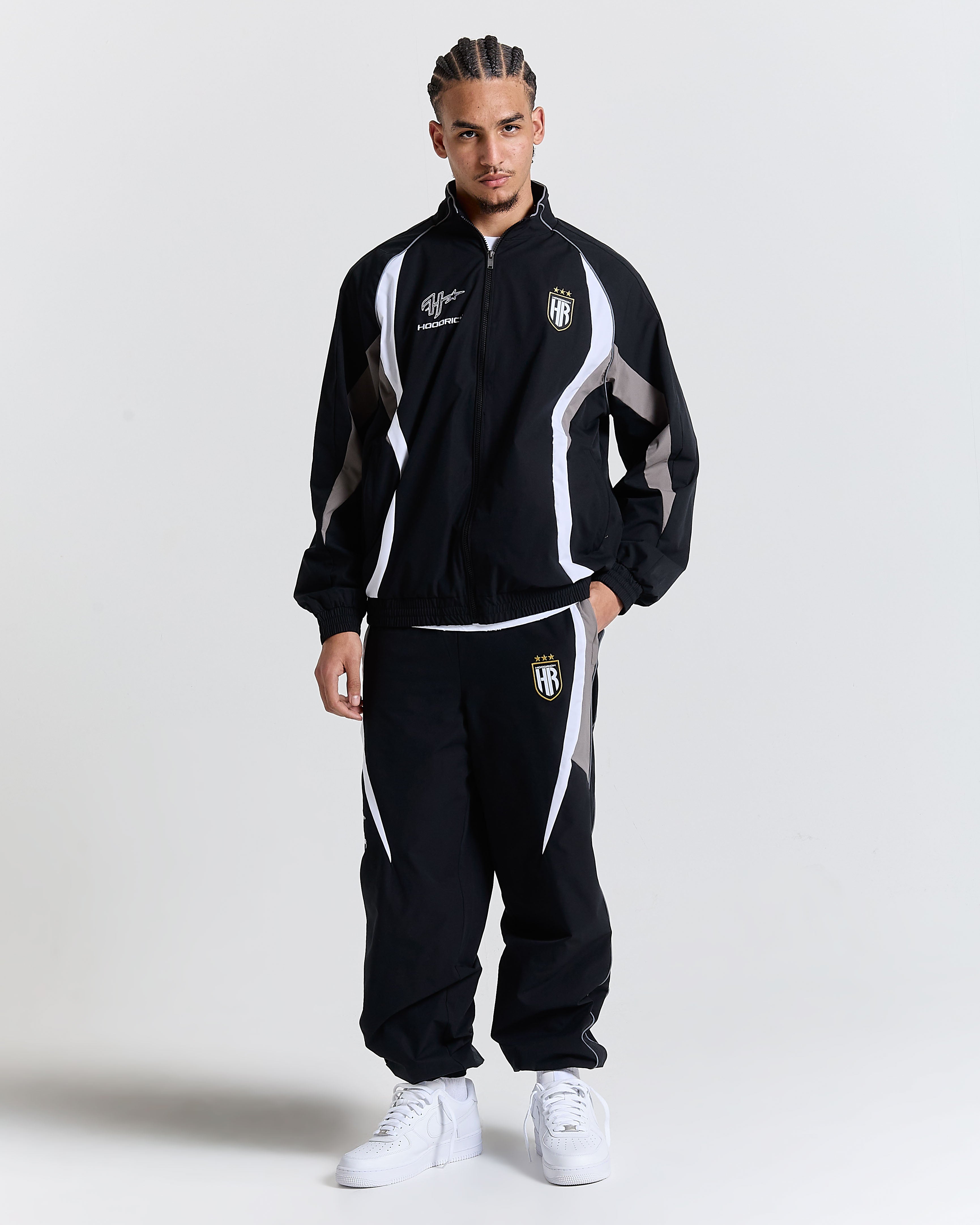 Person wearing a black tracksuit with white accents on a plain background
