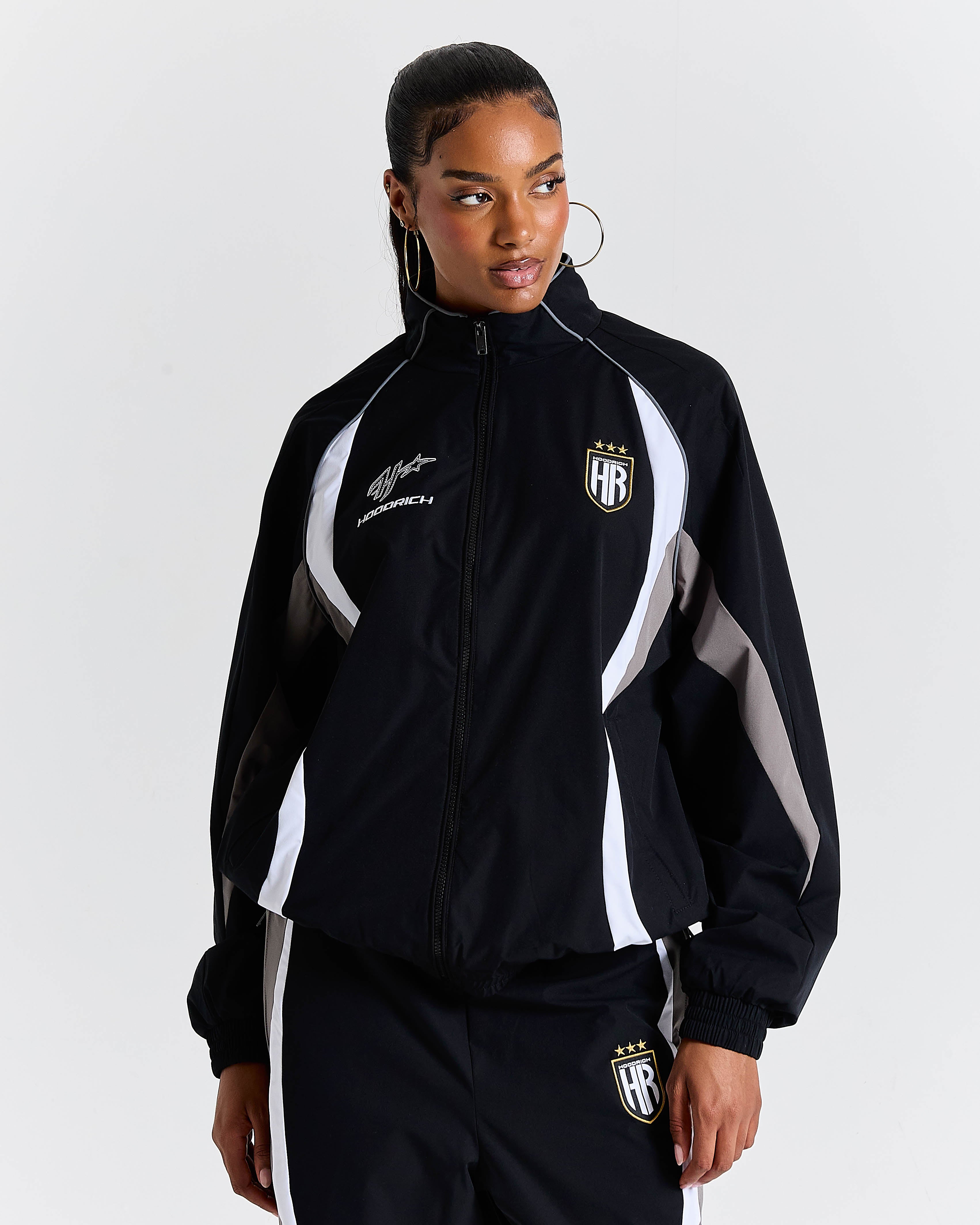 Person wearing a black tracksuit with white accents on a light gray background