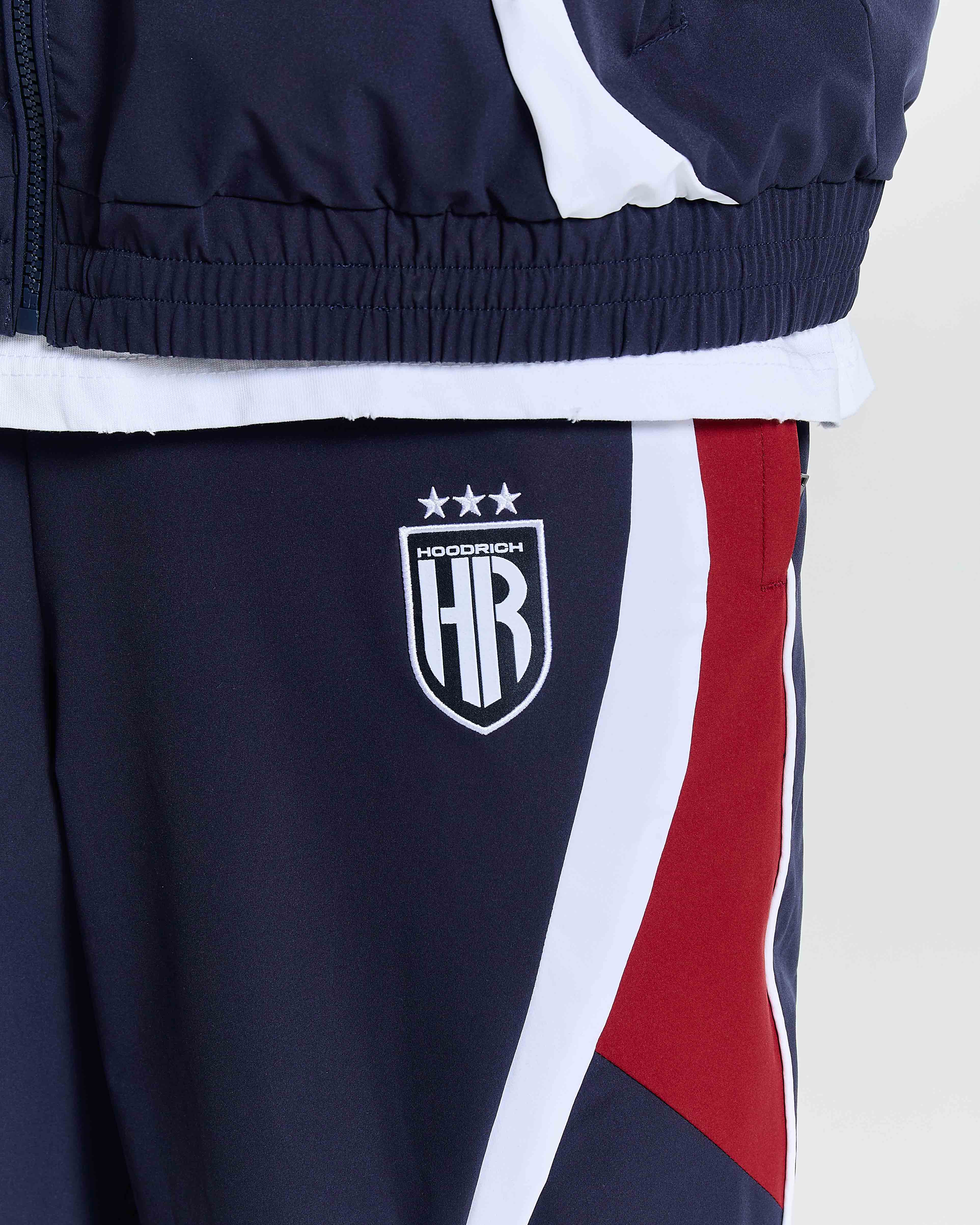 Navy tracksuit with red and white accents featuring a logo on the leg.