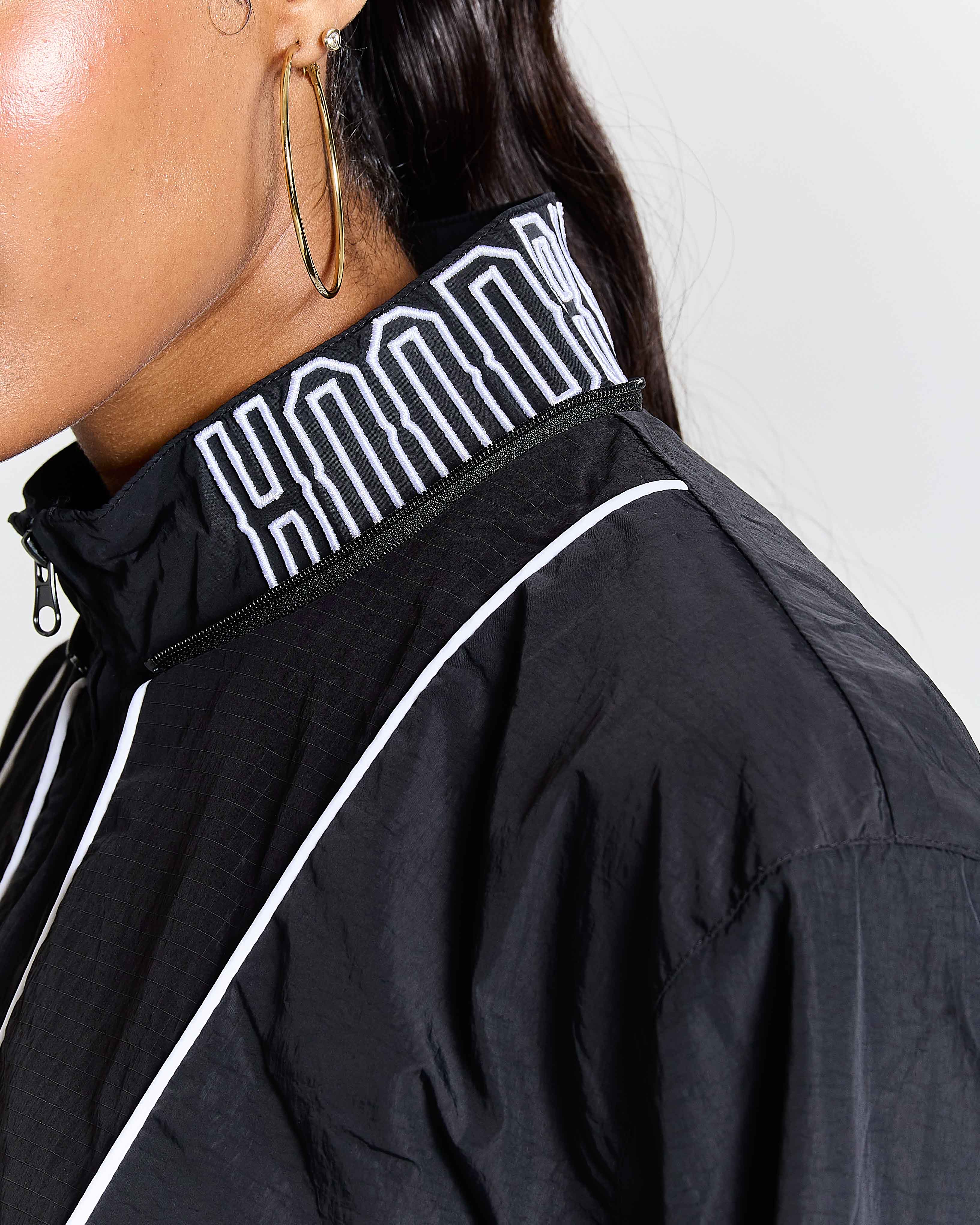 Black jacket with white piping and logo on a plain background