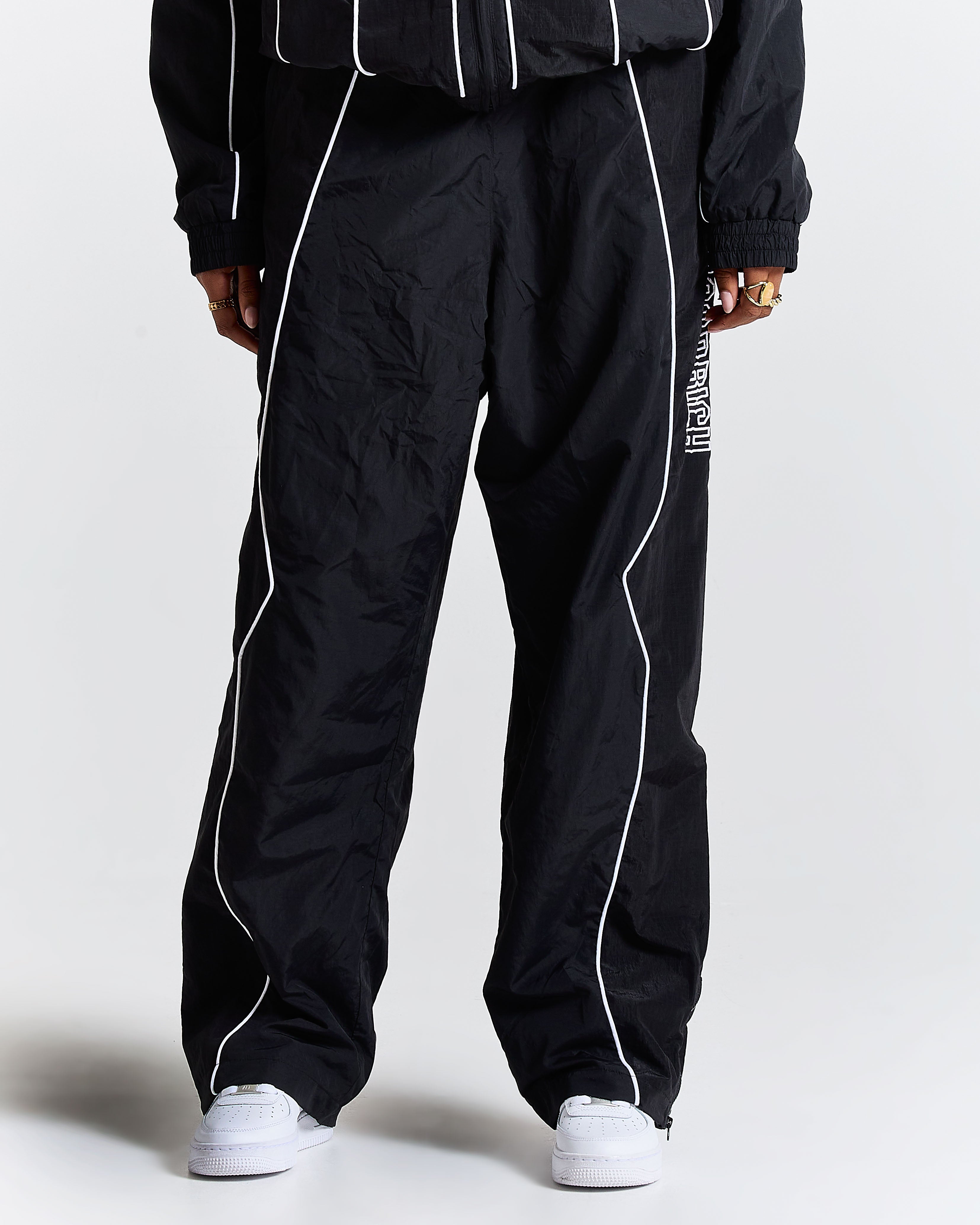 Black tracksuit with white piping on a plain background