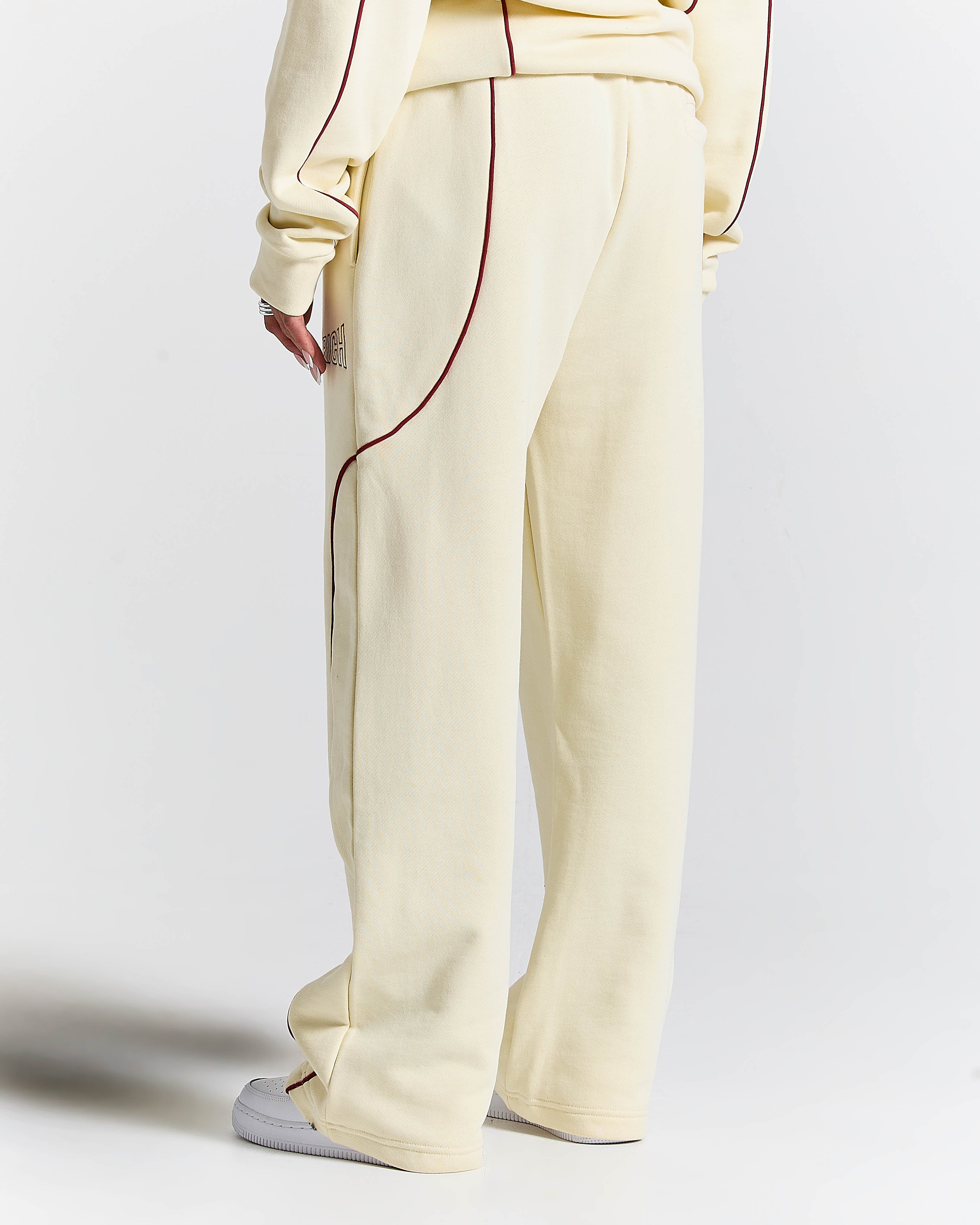 Cream-colored pants with red stitching on a white background