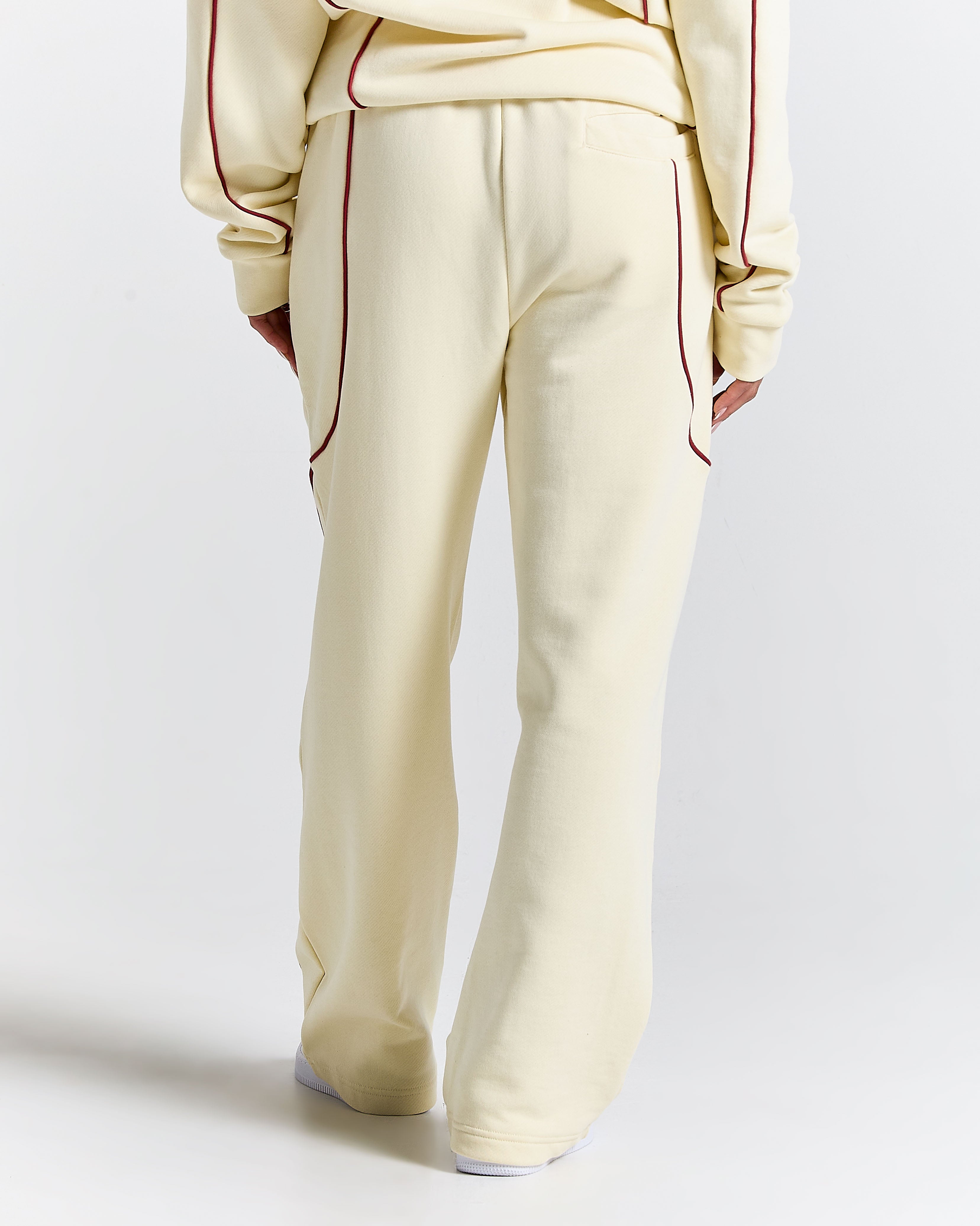 Cream-colored tracksuit with red piping on a light gray background