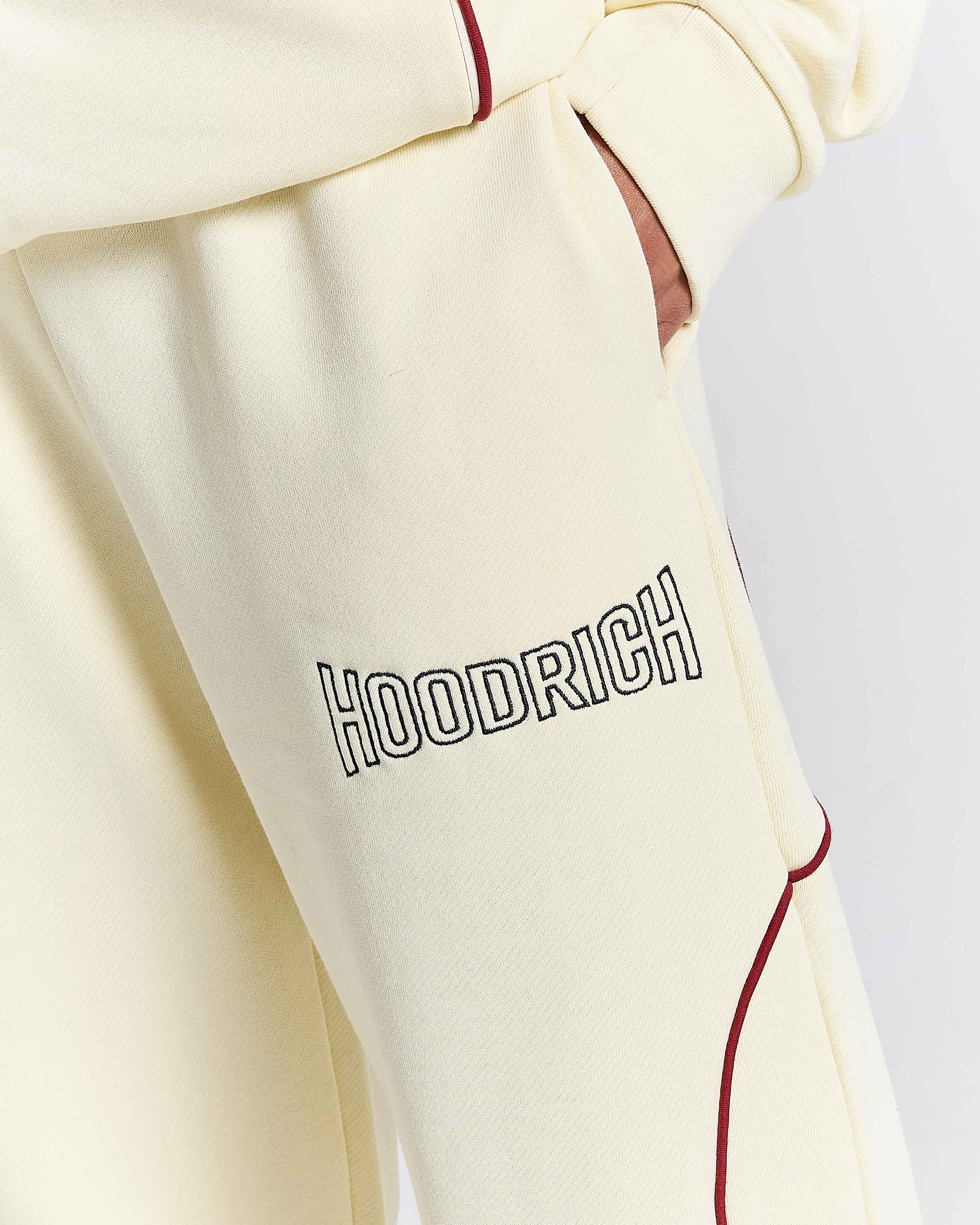 Close-up of a beige hoodie with 'HOODRICH' branding on a light gray background