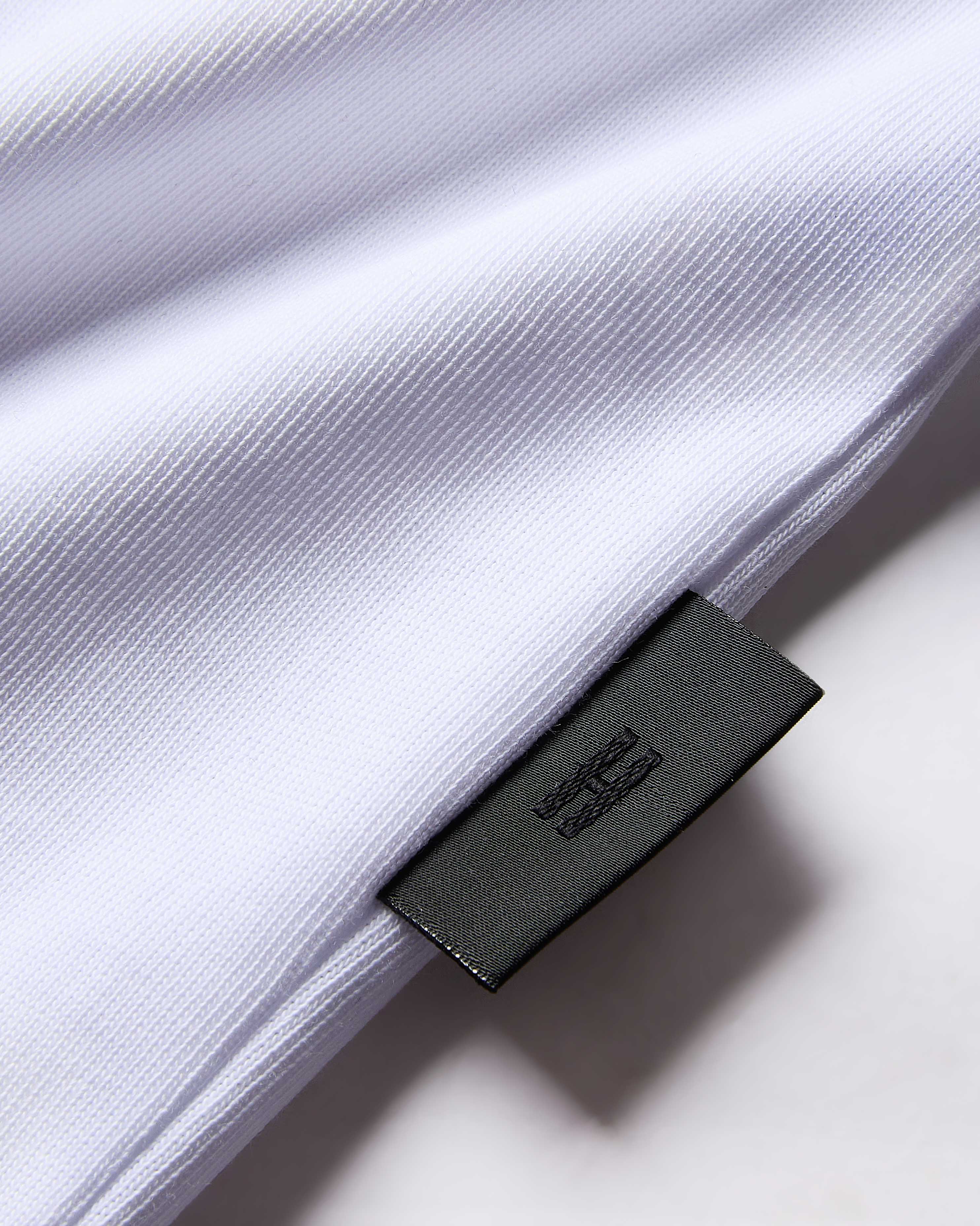 Close-up of a white shirt with a black label on a light background