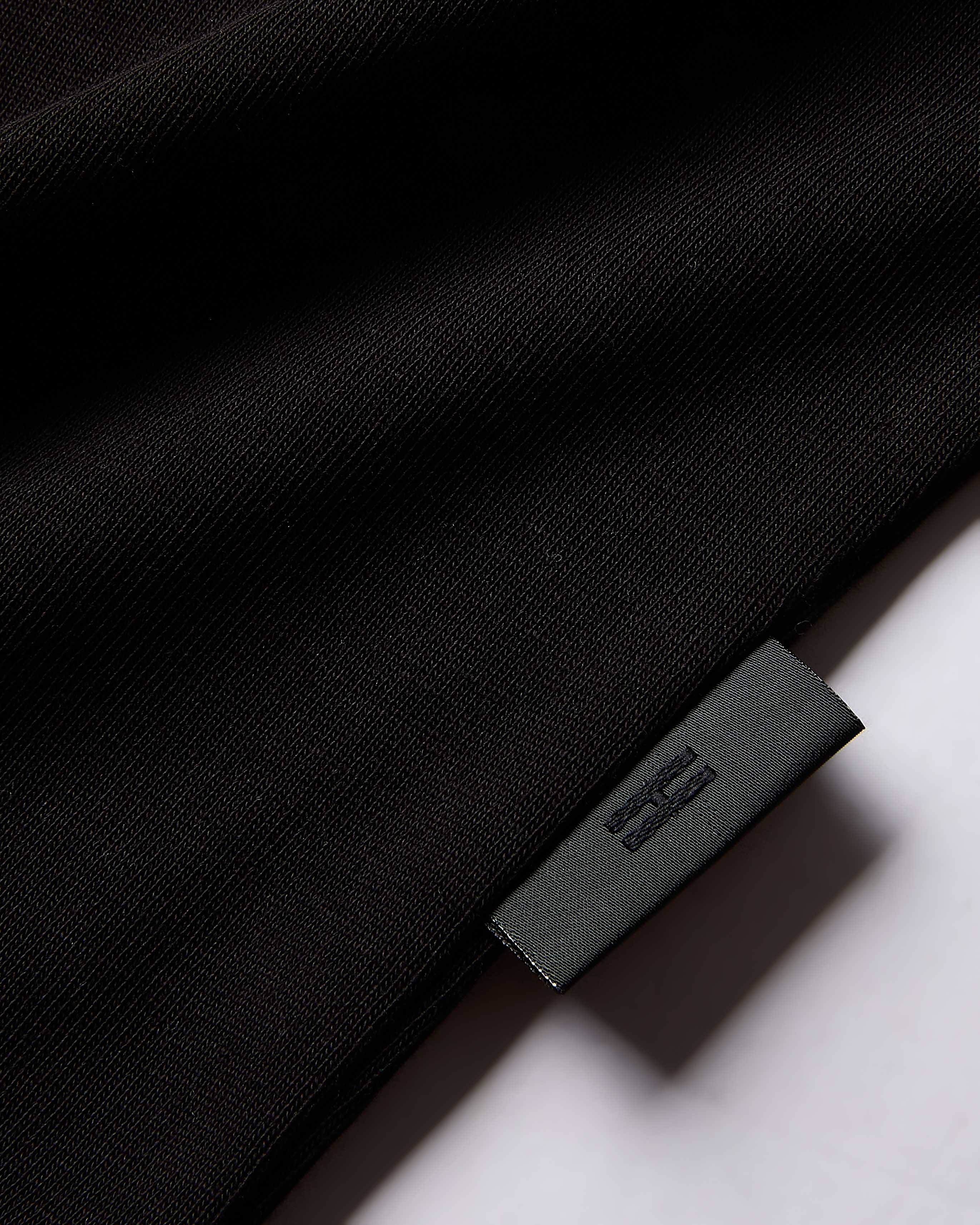 Close-up of a black garment with a brand label on a white background