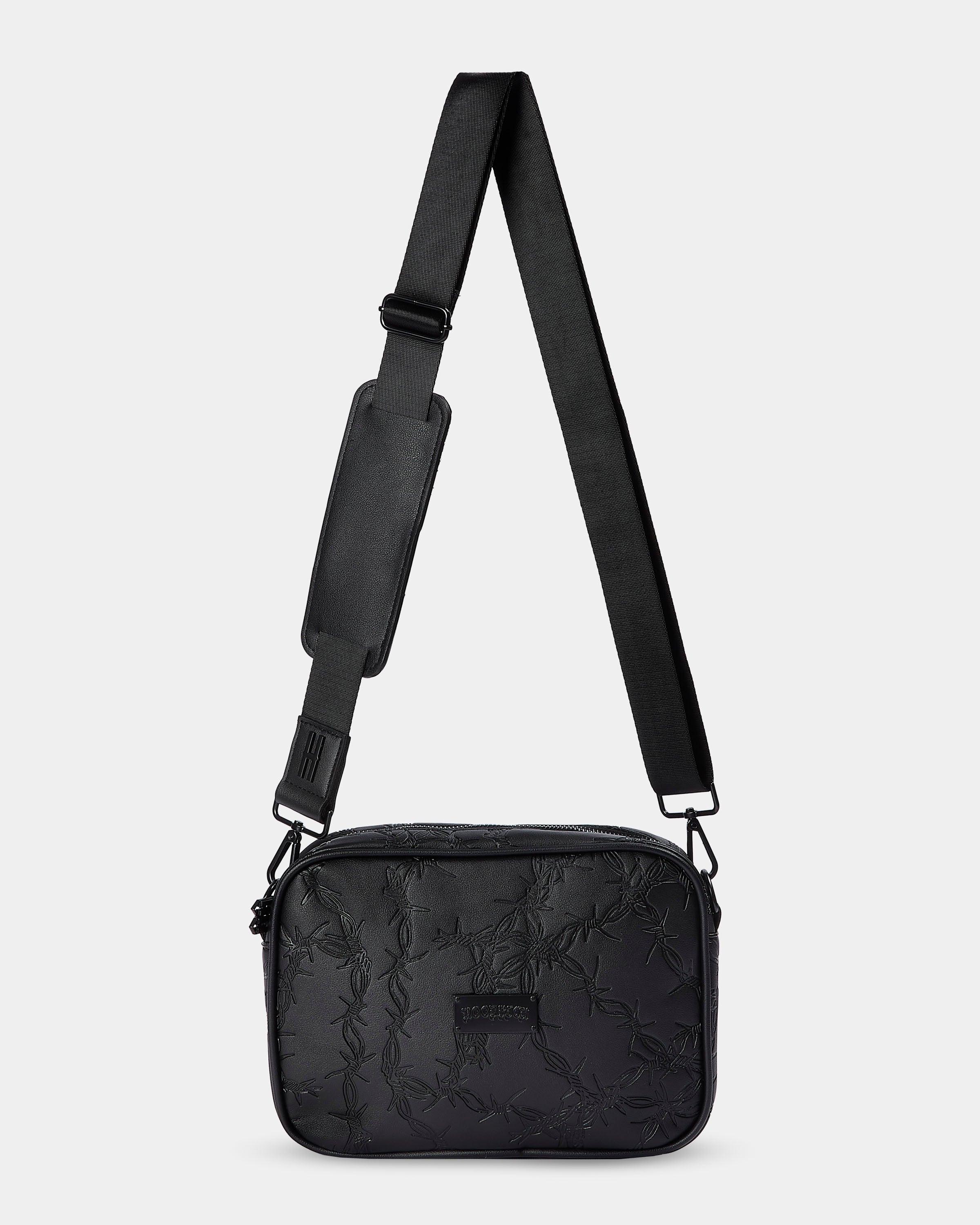 Black quilted crossbody bag with a strap on a light gray background
