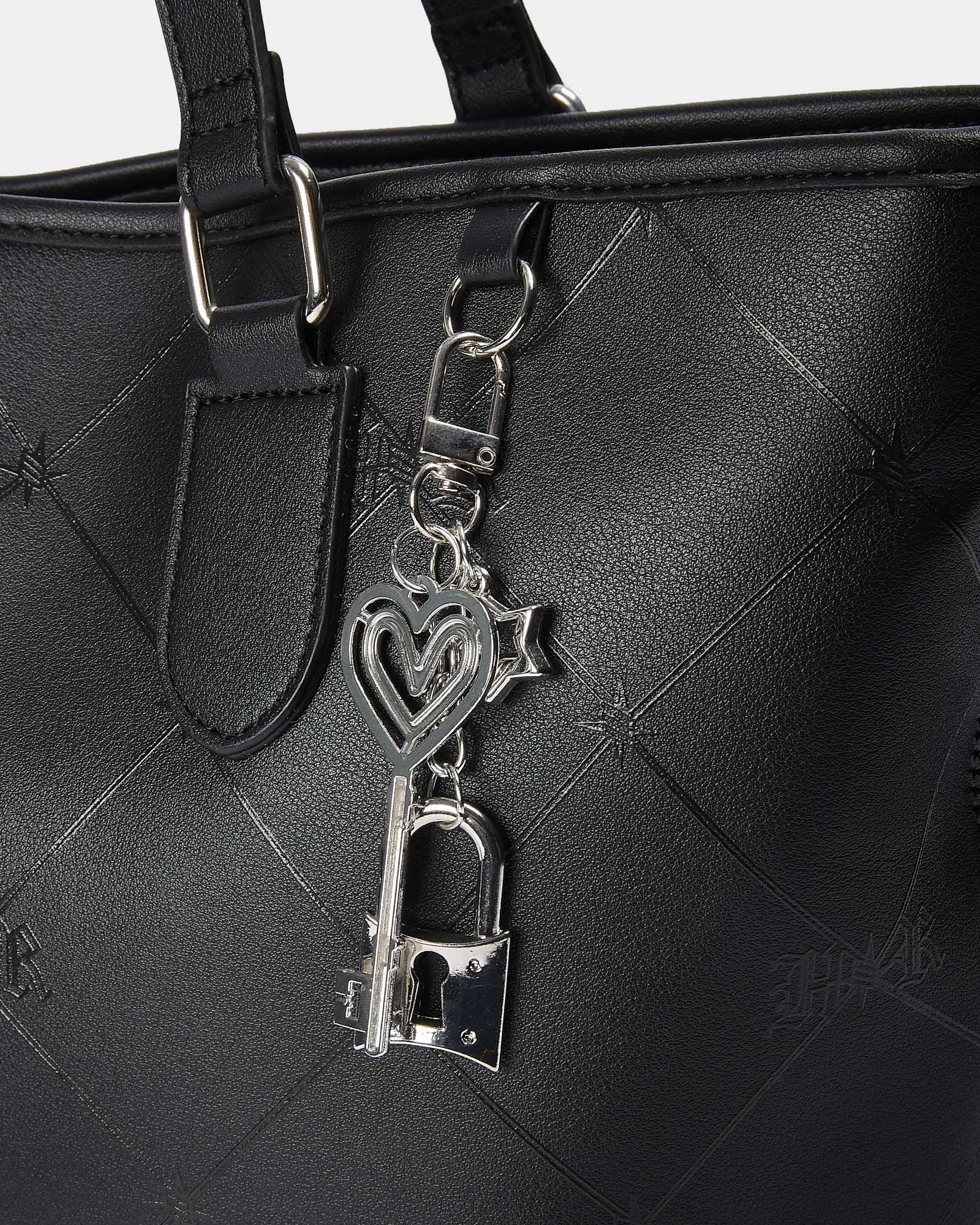 Black handbag with a silver key-shaped charm on a gray background