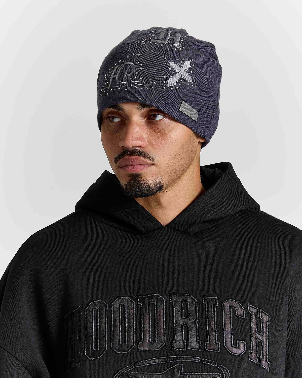 Displays a model wearing the grey 'Hoodrich' branded Scar Knitted Fitted Beanie