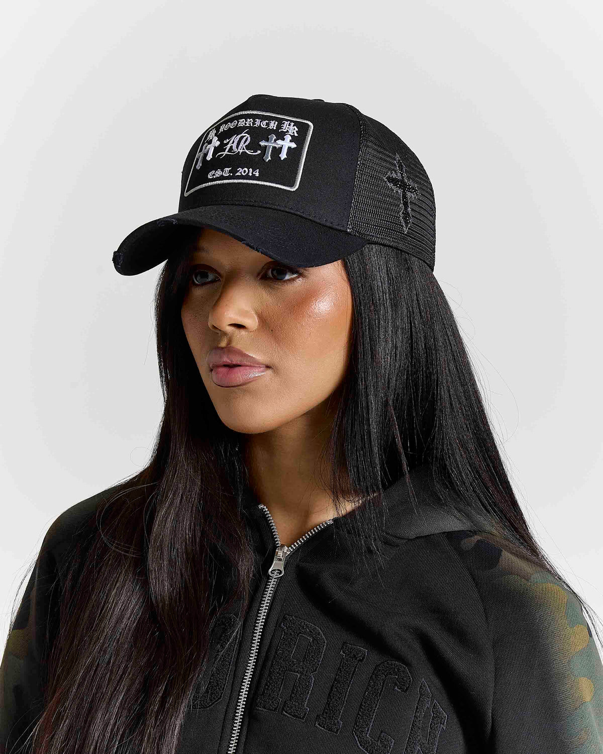 Displays a model wearing the black & grey 'Hoodrich' branded Nocturn Trucker Cap