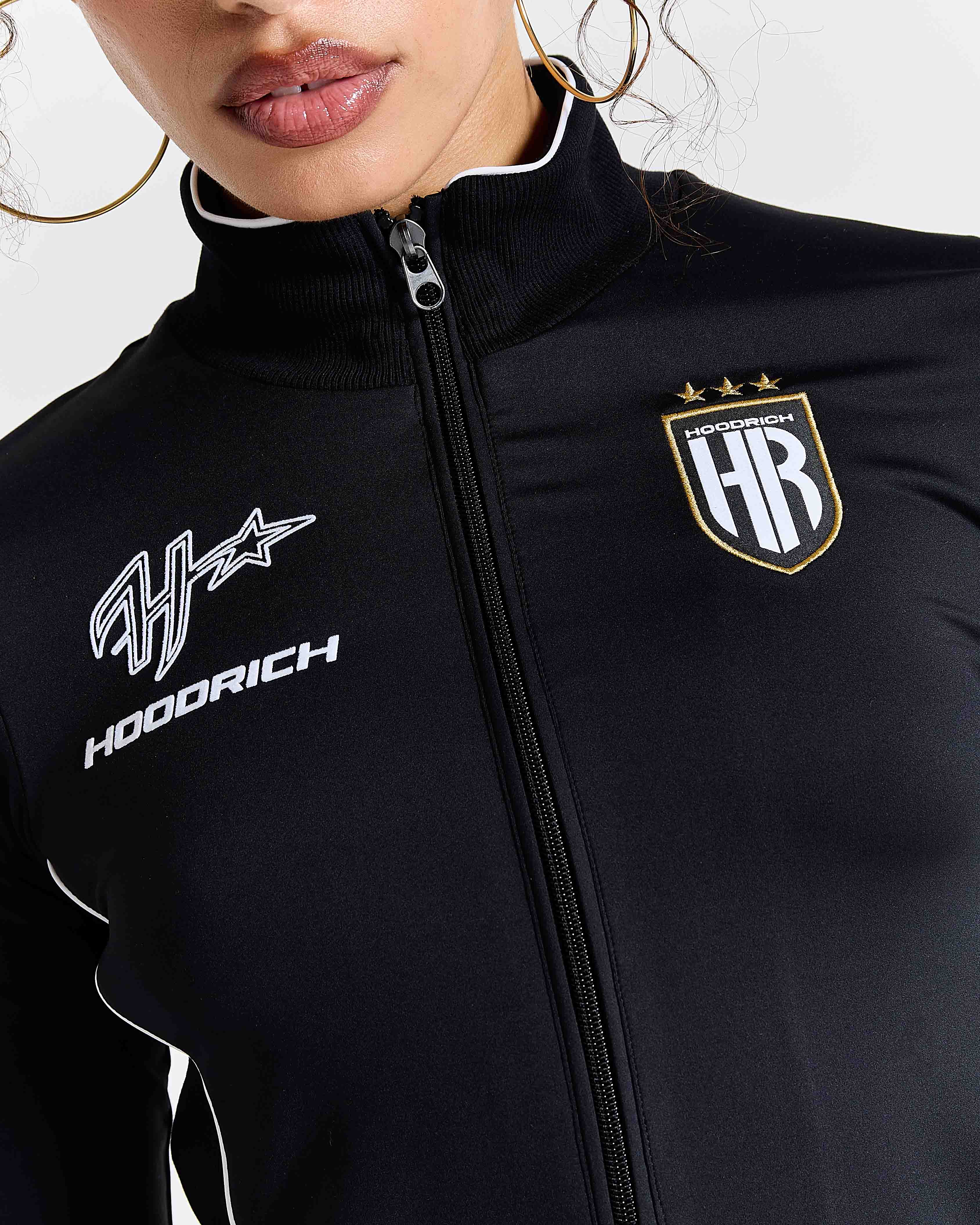 Displays a model wearing the Black 'Hoodrich' branded women's Glide Football Full Tracksuit