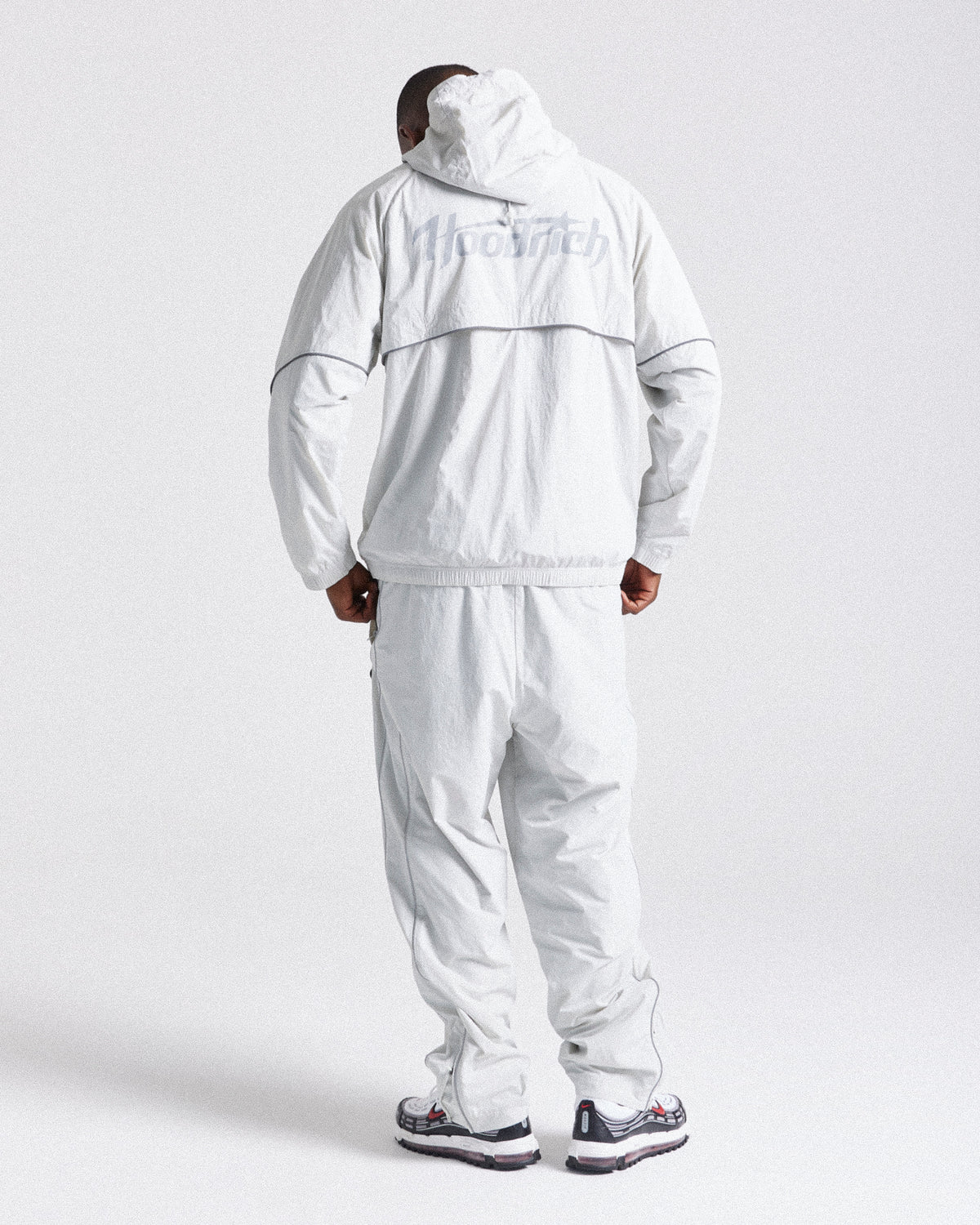 Displays a model wearing the Grey 'Hoodrich' branded men's Cypher Woven Full Tracksuit