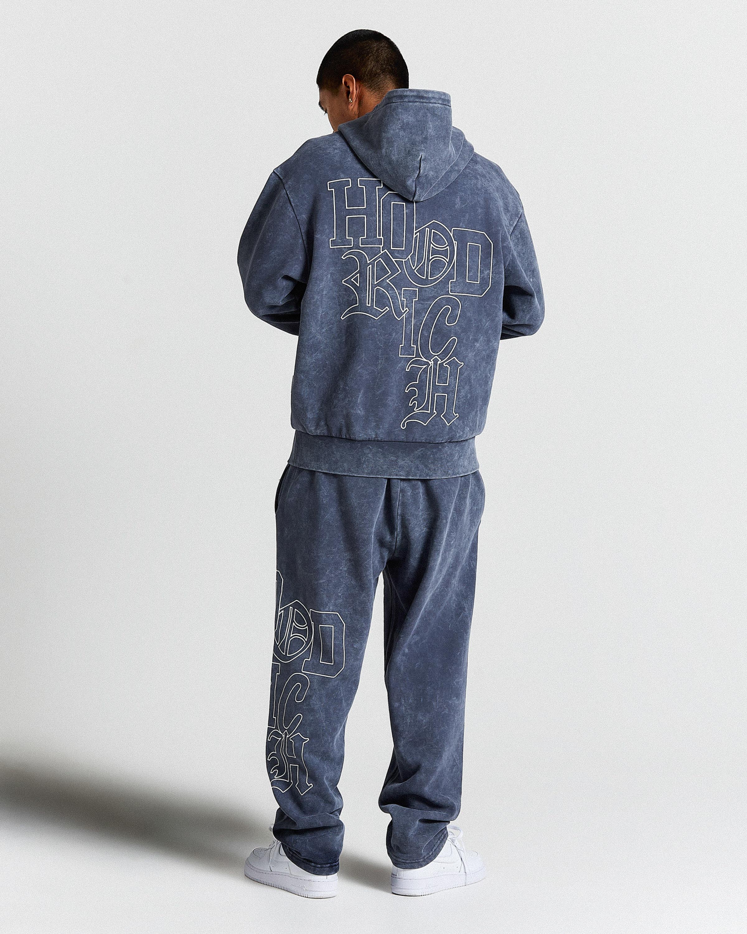 Person wearing a blue tracksuit with 'Hoodrich' text on the back against a white background
