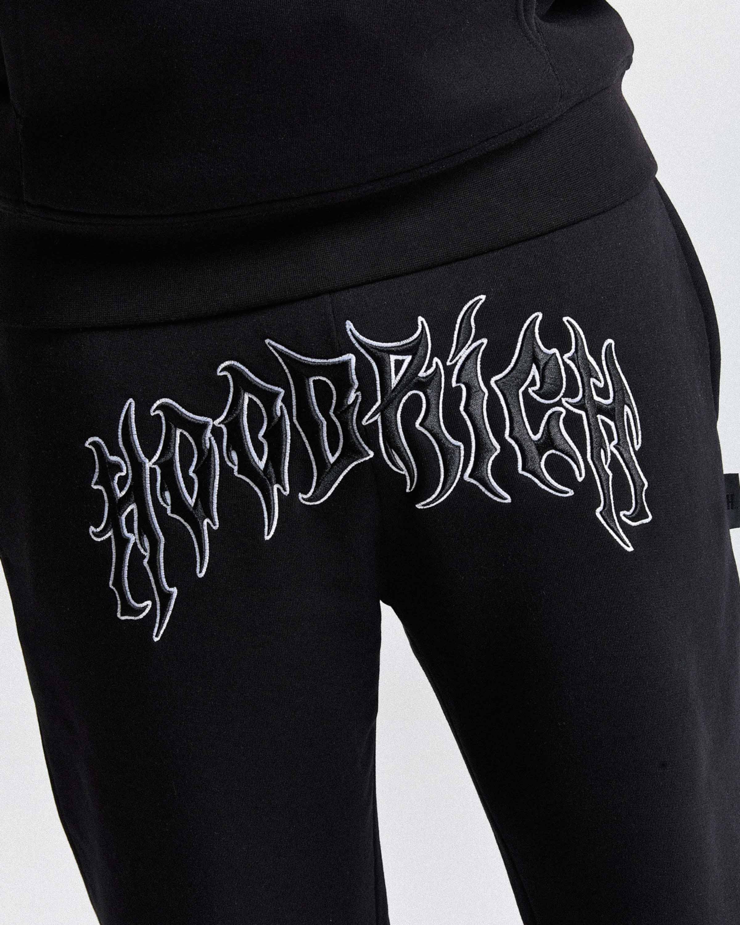 Black sweatpants with white embroidered text on a light gray background