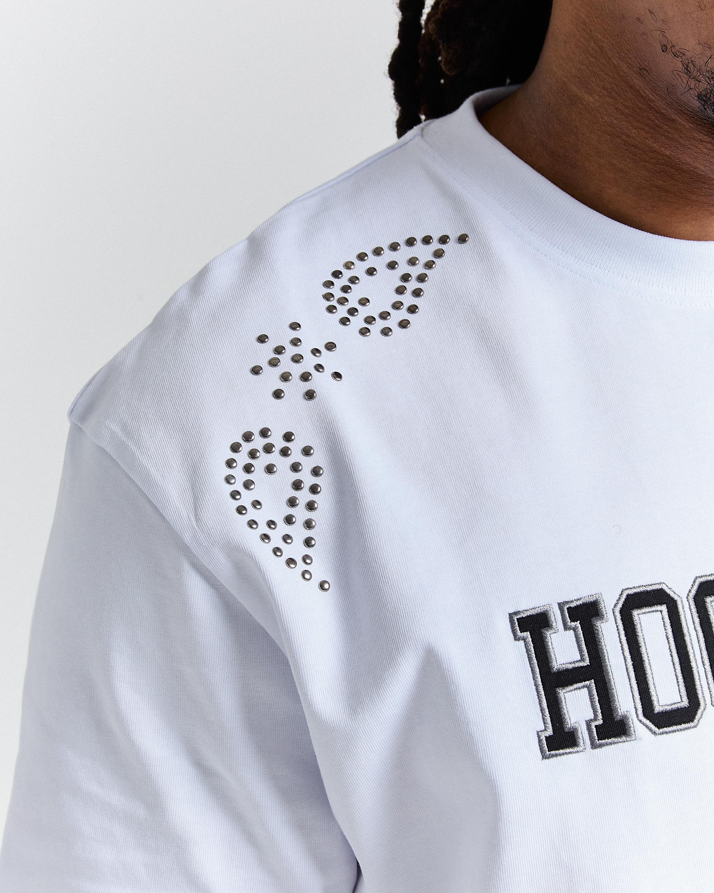 White sweatshirt with decorative patterns on the shoulder - on a plain background