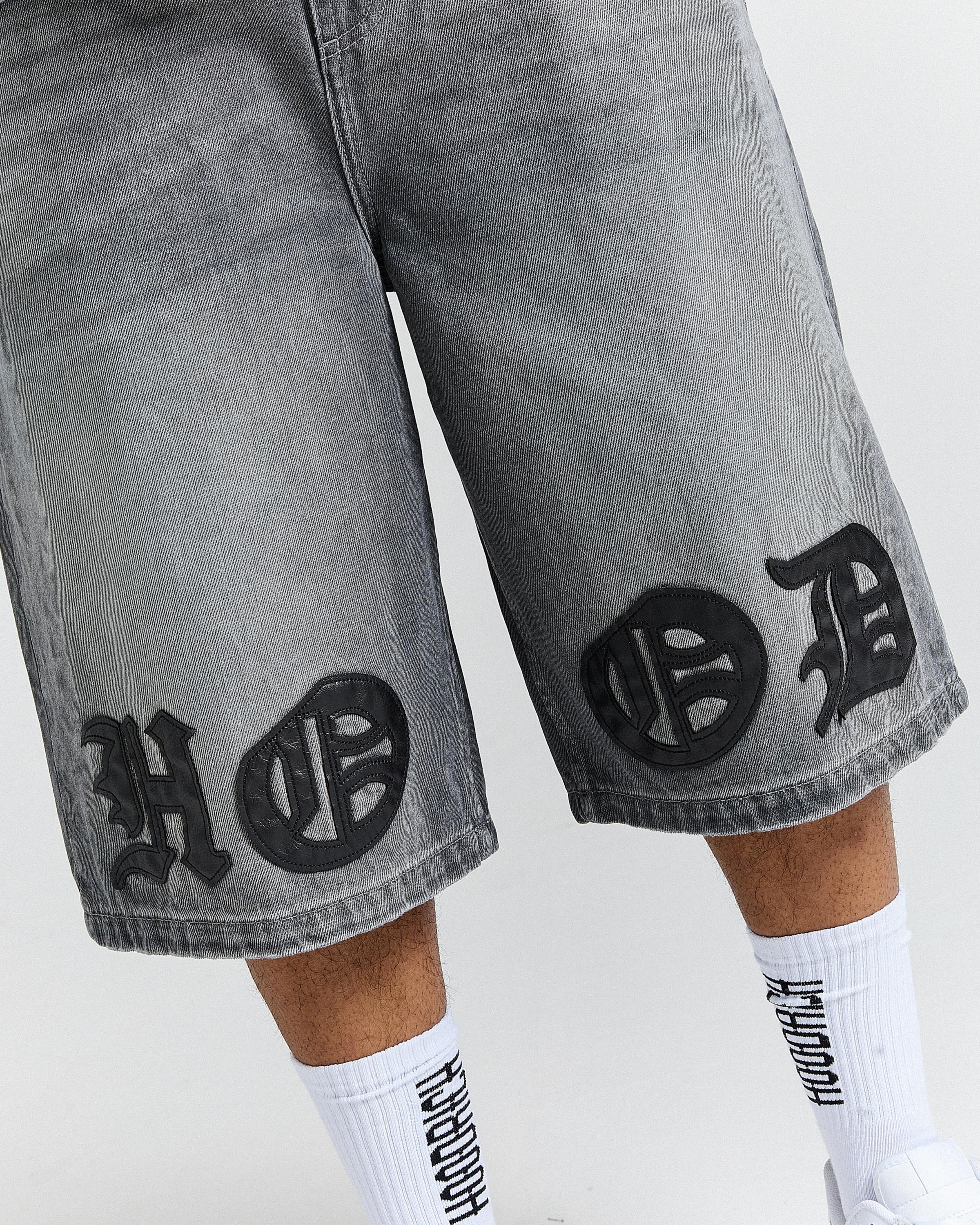 Gray shorts with black patterns and white socks worn by a person on a white background