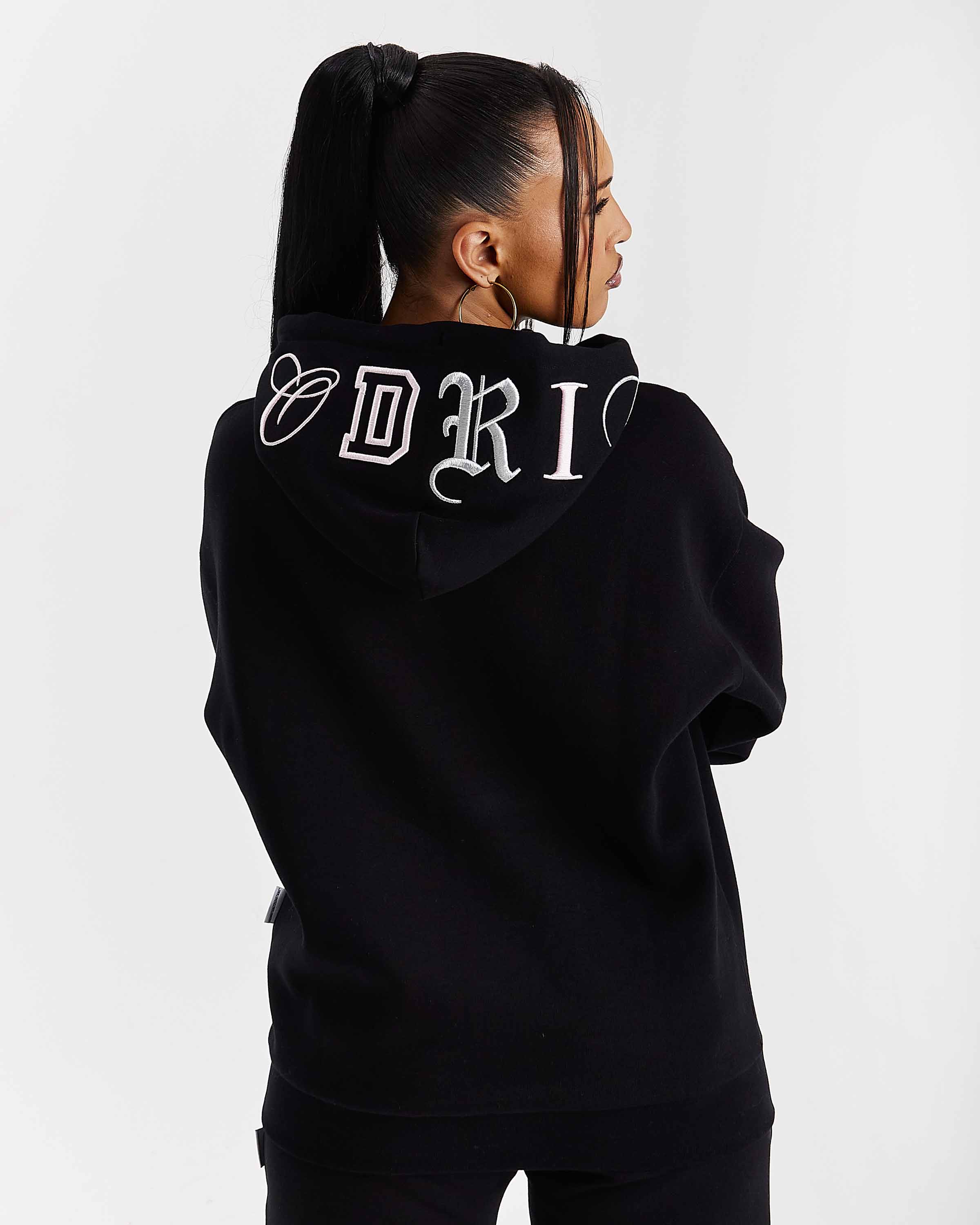 Person wearing a black hoodie with the branding on the back against a white background