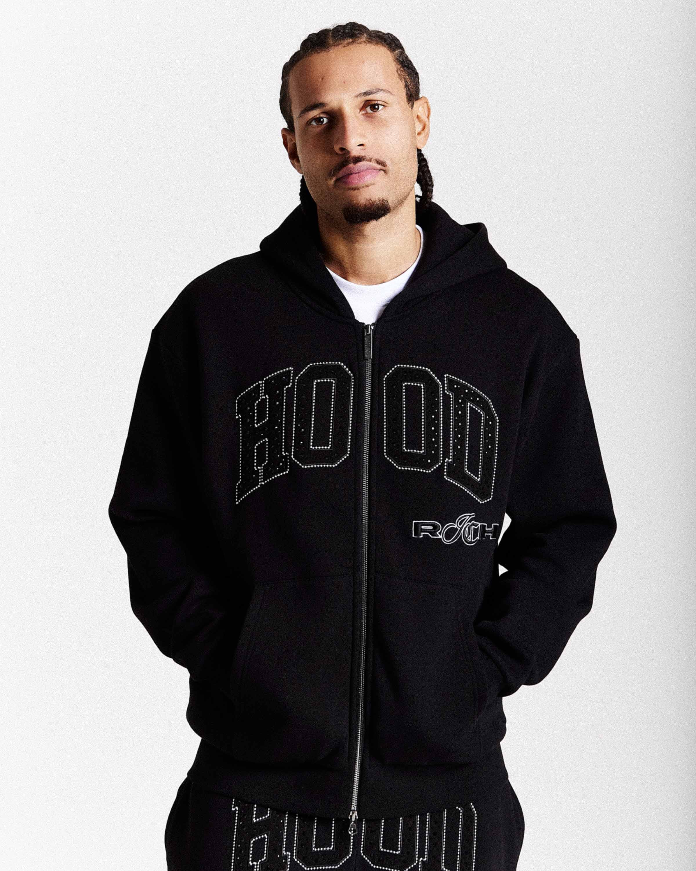 Man wearing a black hoodie with 'HOODRICH' text on a white background