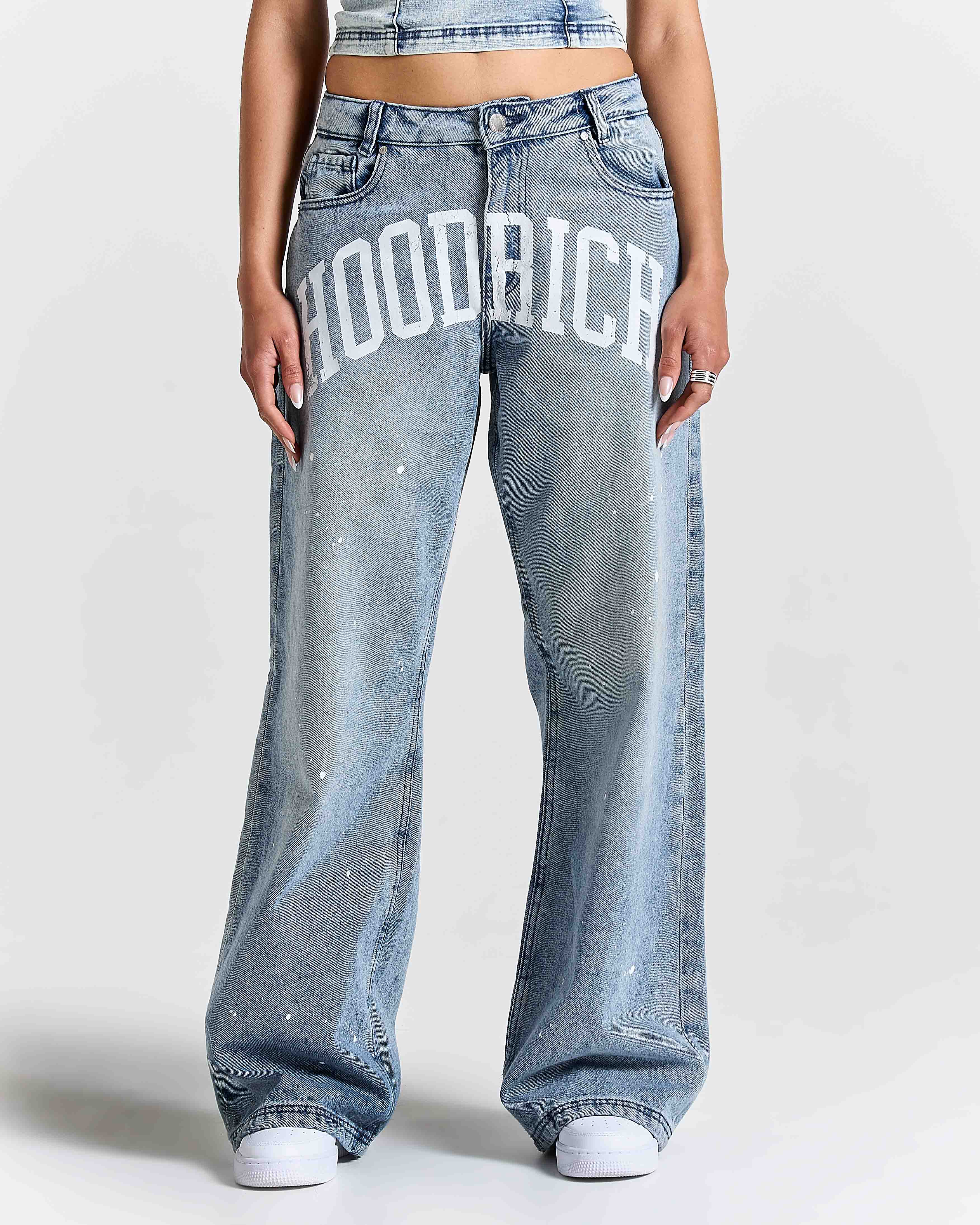 Person wearing blue jeans with 'Hoodrich' branding on a white background