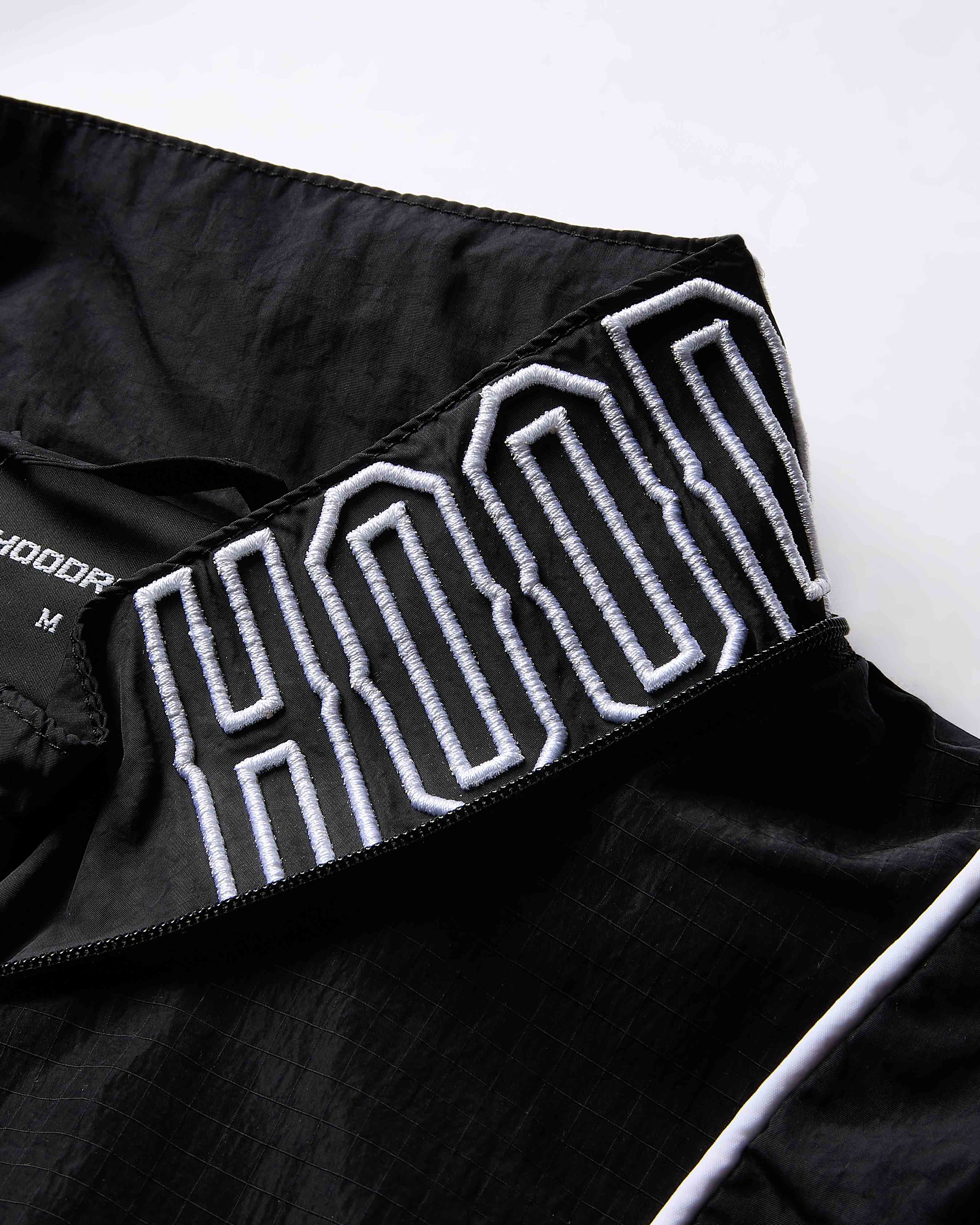 Black jacket with white embroidered text on a white background