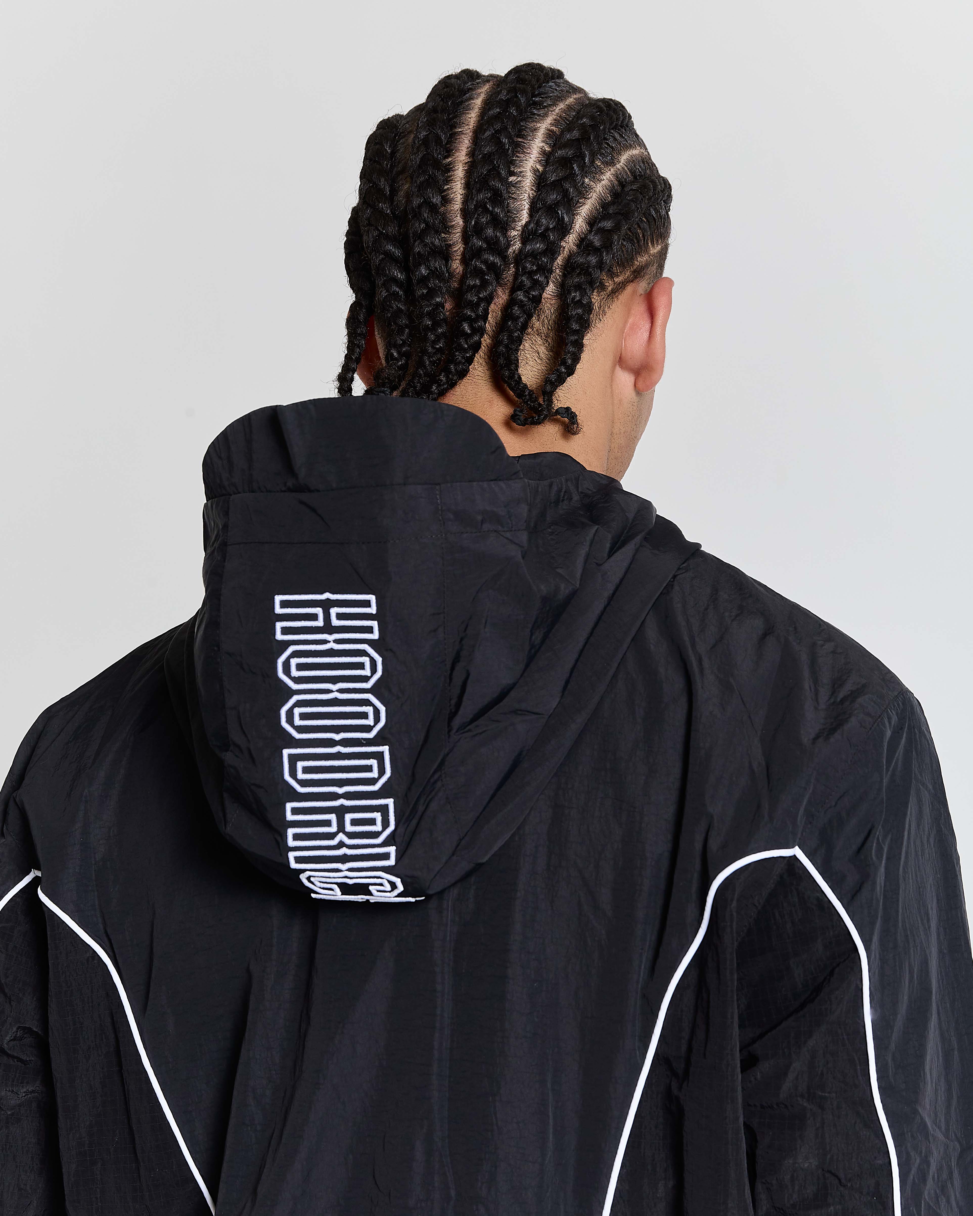 Person wearing a black jacket with 'HOODRIG' branding on the back against a light gray background