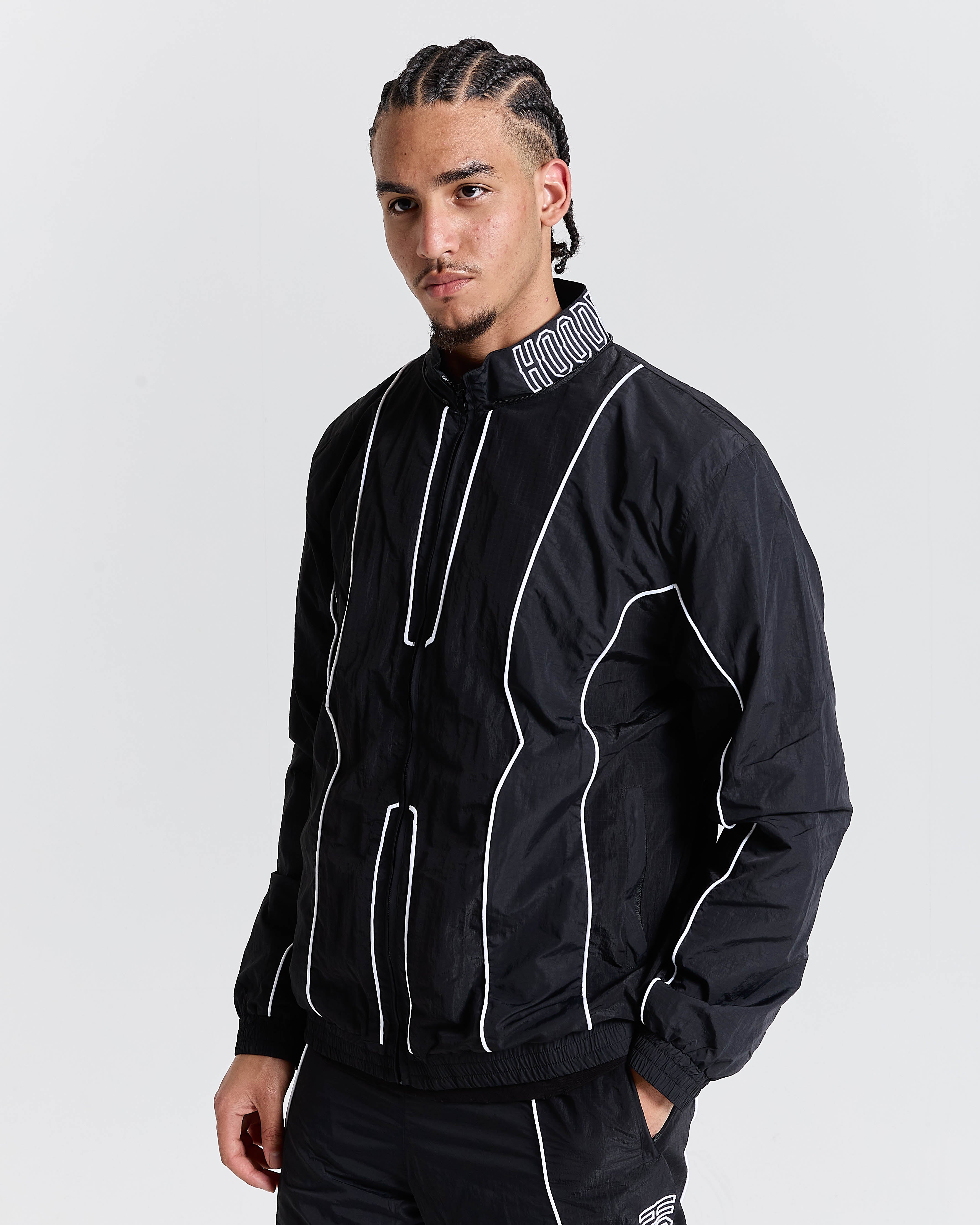 Person wearing a black jacket with white accents on a gray background