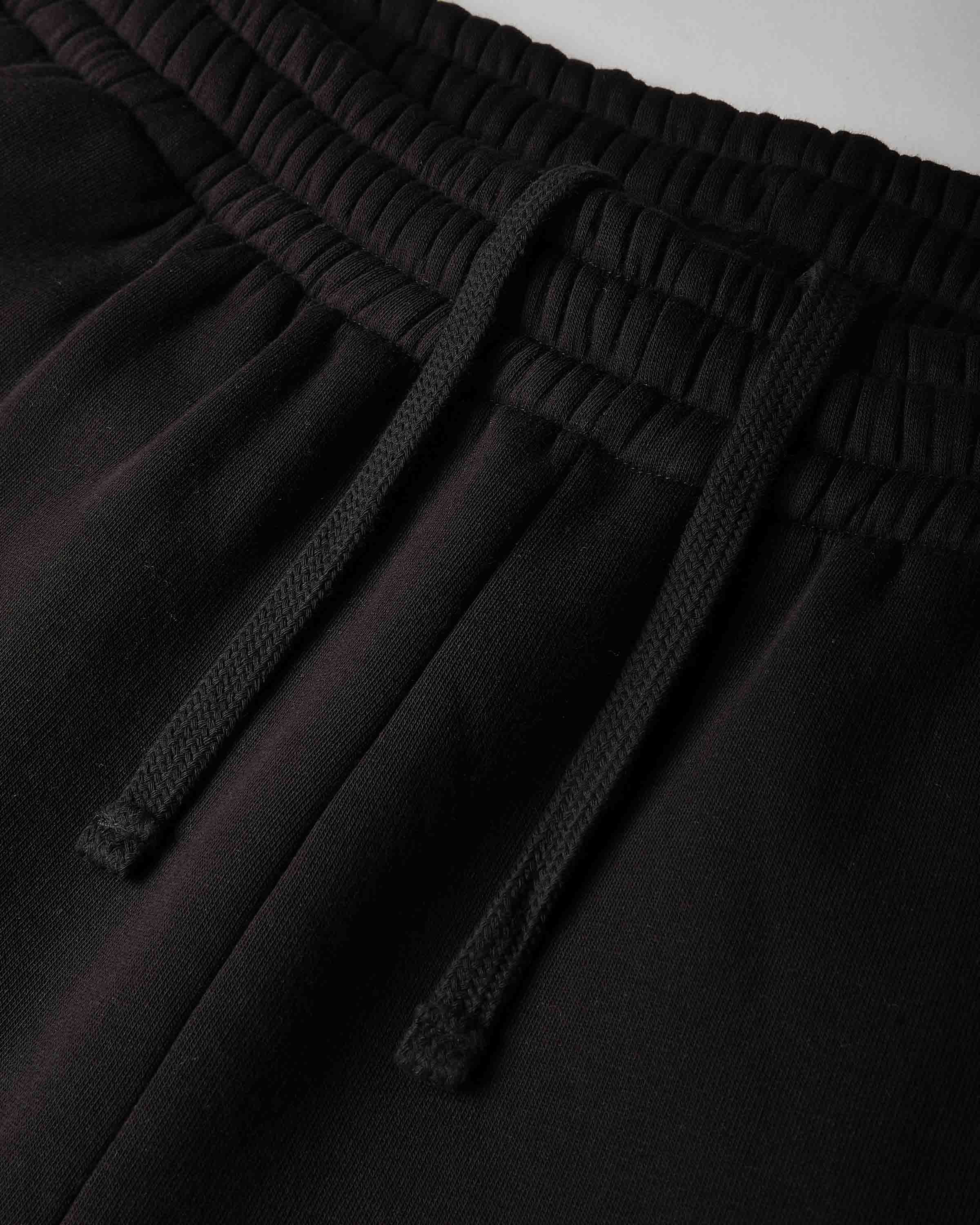 Close-up of black drawstring sweatpants showing the elastic waistband and textured drawstrings.