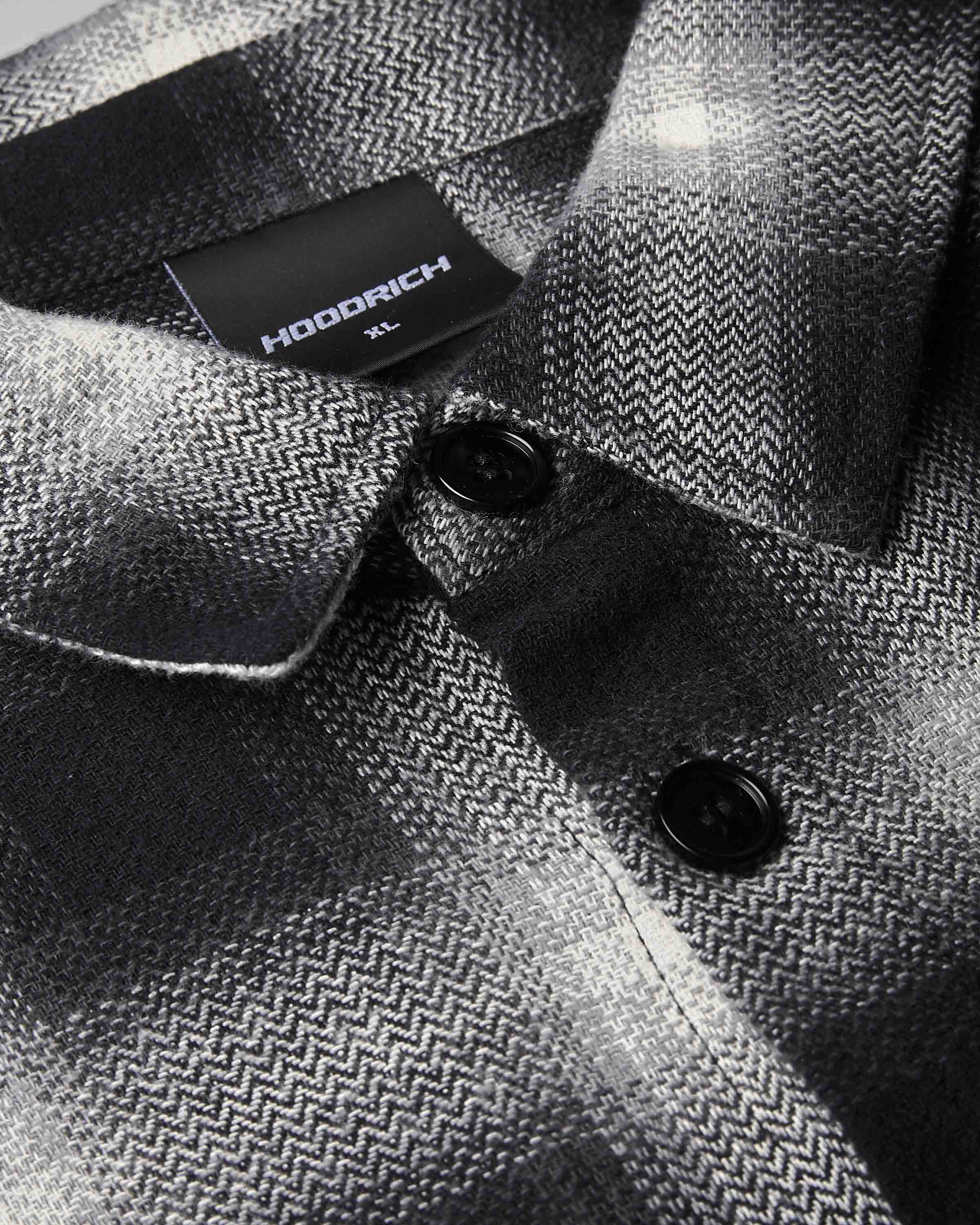 Close-up of a HODDRICH men's button-down shirt featuring a black and gray herringbone pattern, with a black brand label visible on the collar.