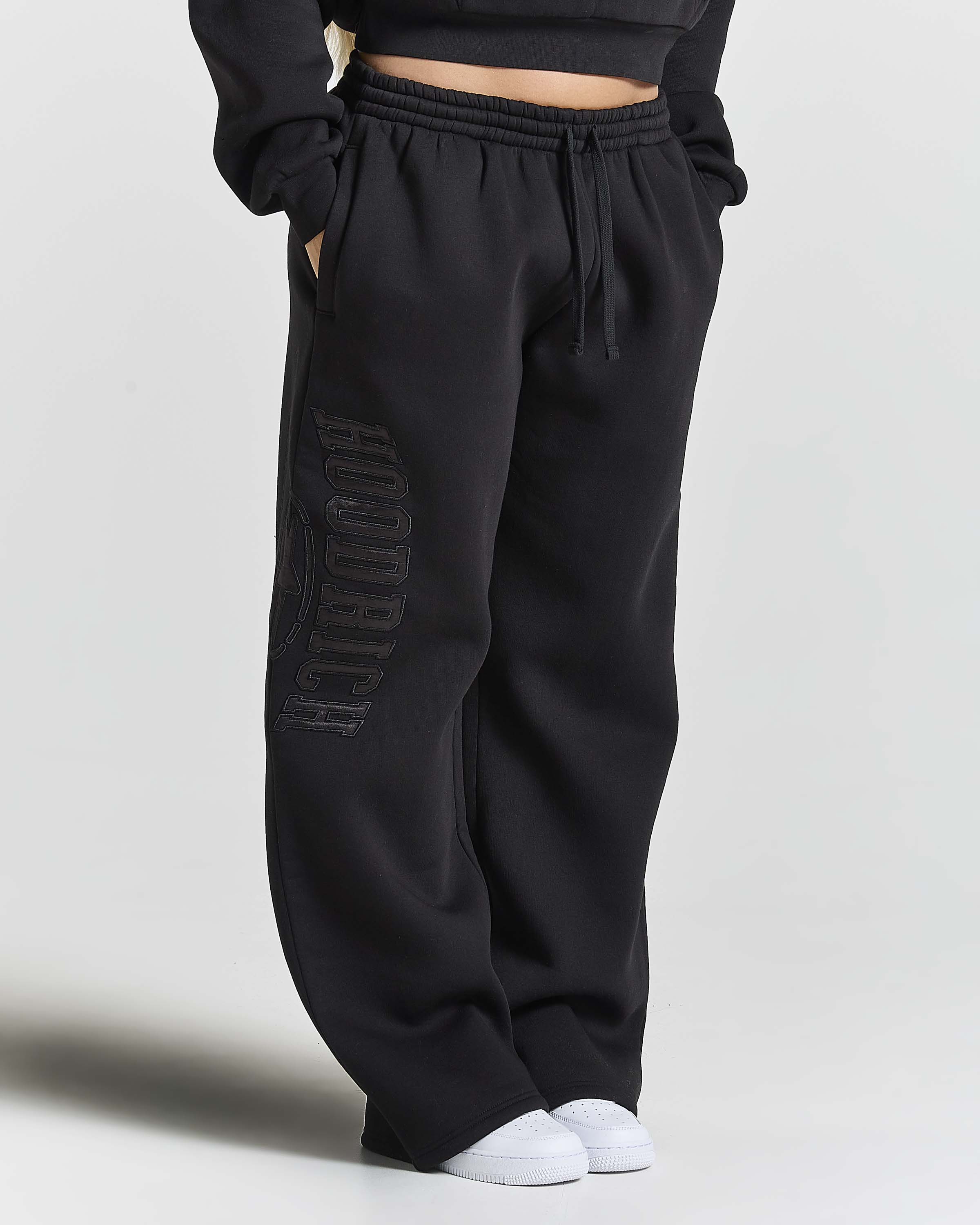 Displays a women wearing the Black 'Hoodrich' branded women's Aegis Full Tracksuit