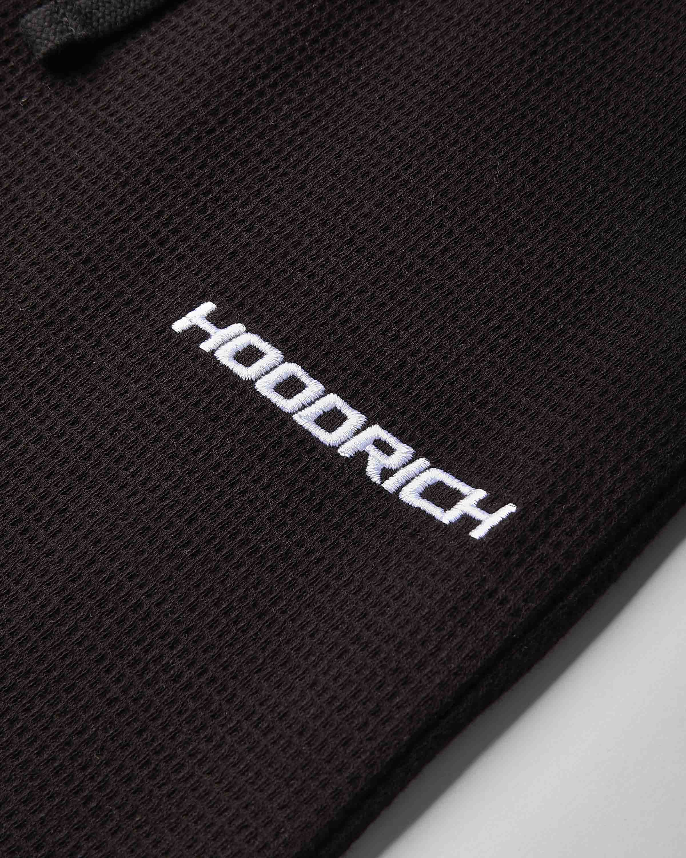 Close-up of a black textured mesh fabric with the brand name 'HOODRICH' printed in white across the center.