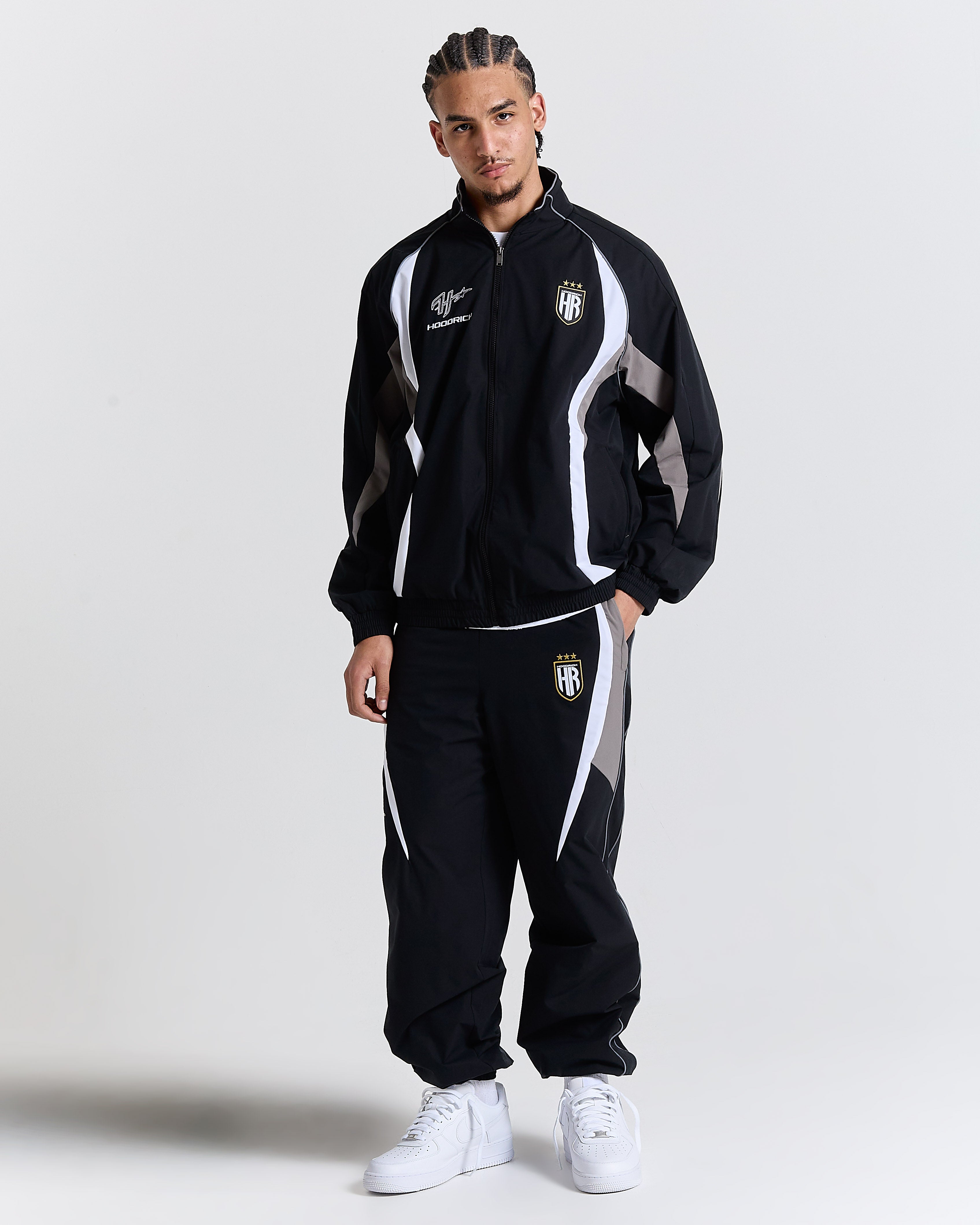 Person wearing a black tracksuit with white accents on a light gray background