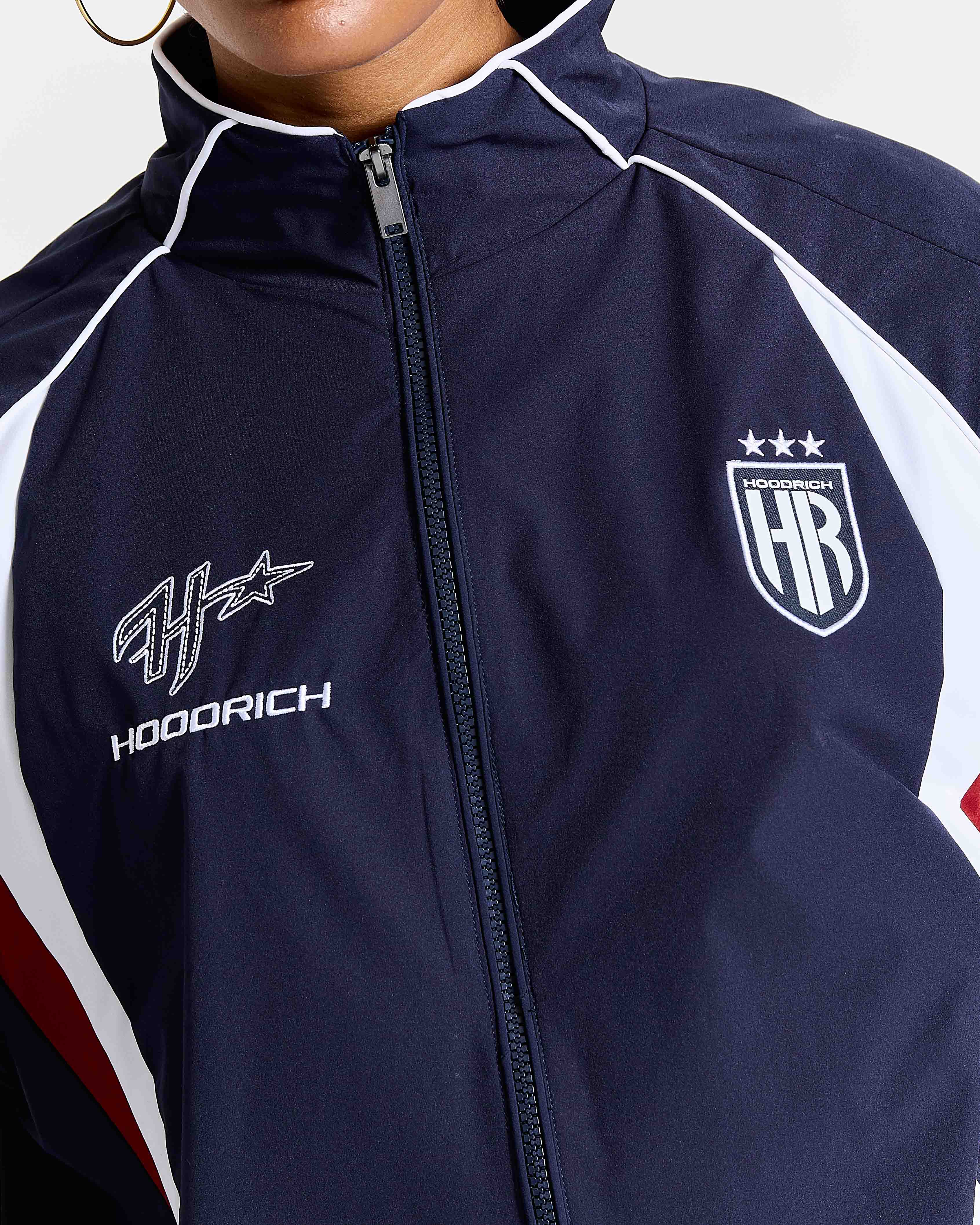 Navy blue jacket with white accents and brand logos on a white background