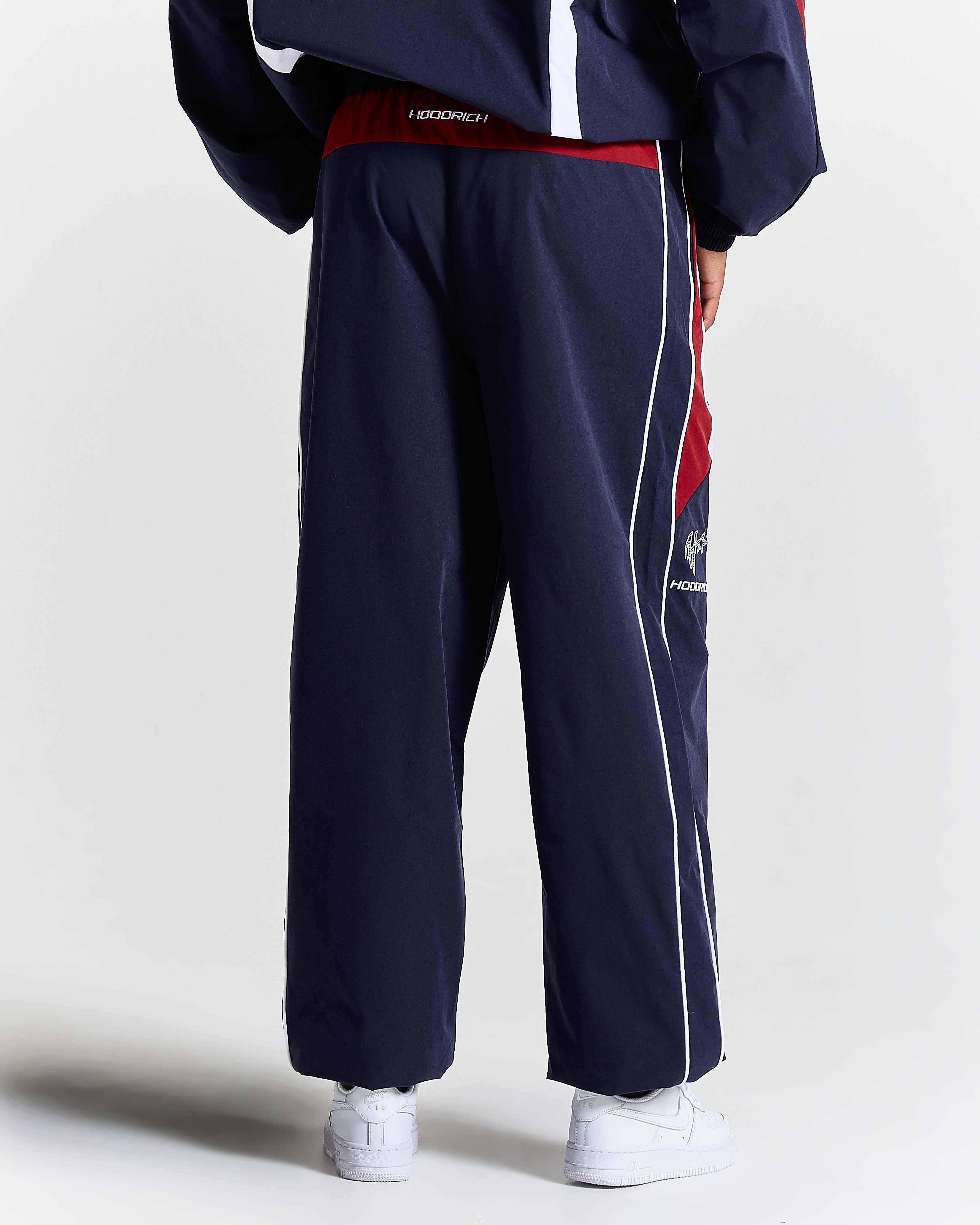 Navy tracksuit with red and white accents on a plain background