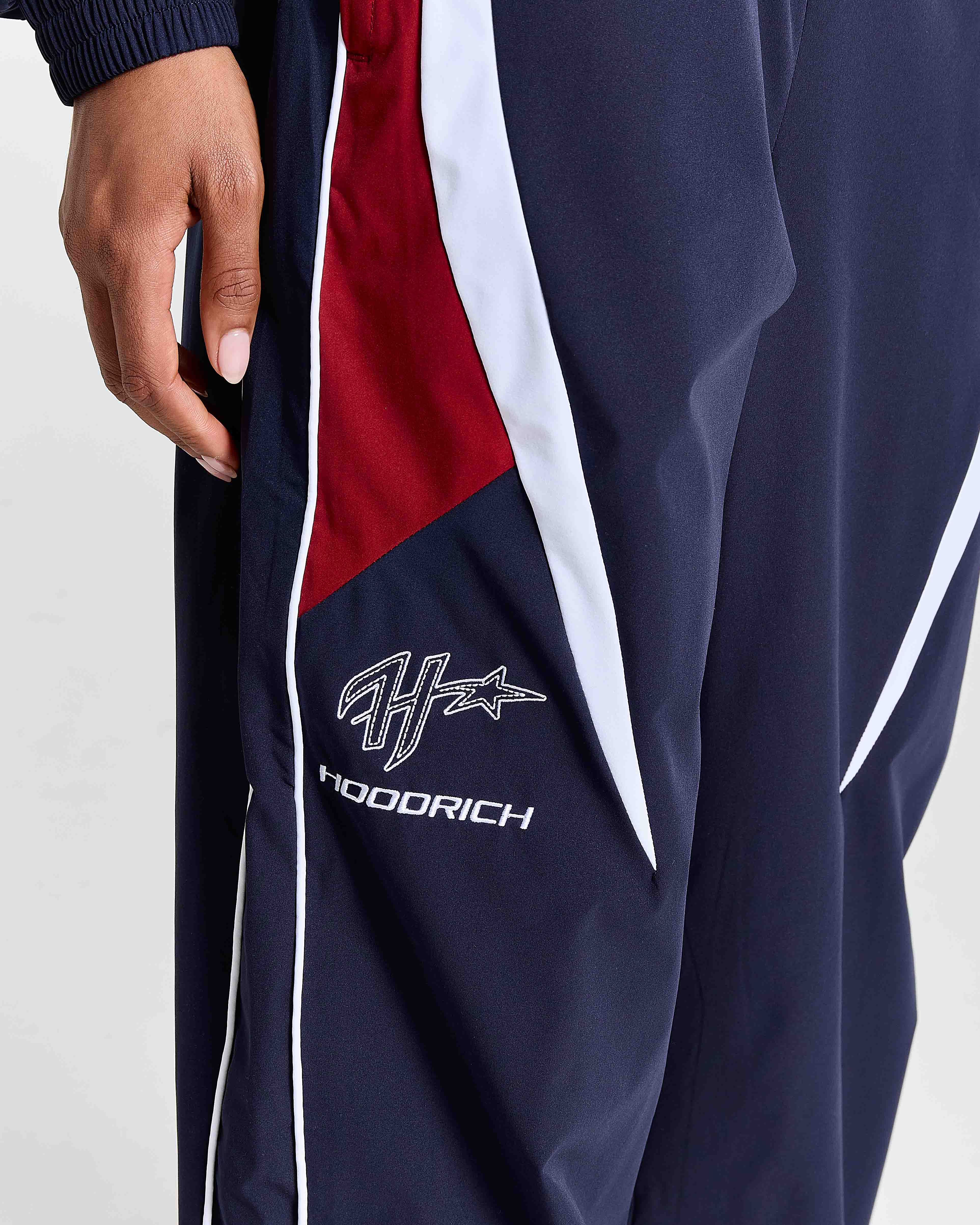 Navy tracksuit with red and white accents featuring a logo on a light gray background