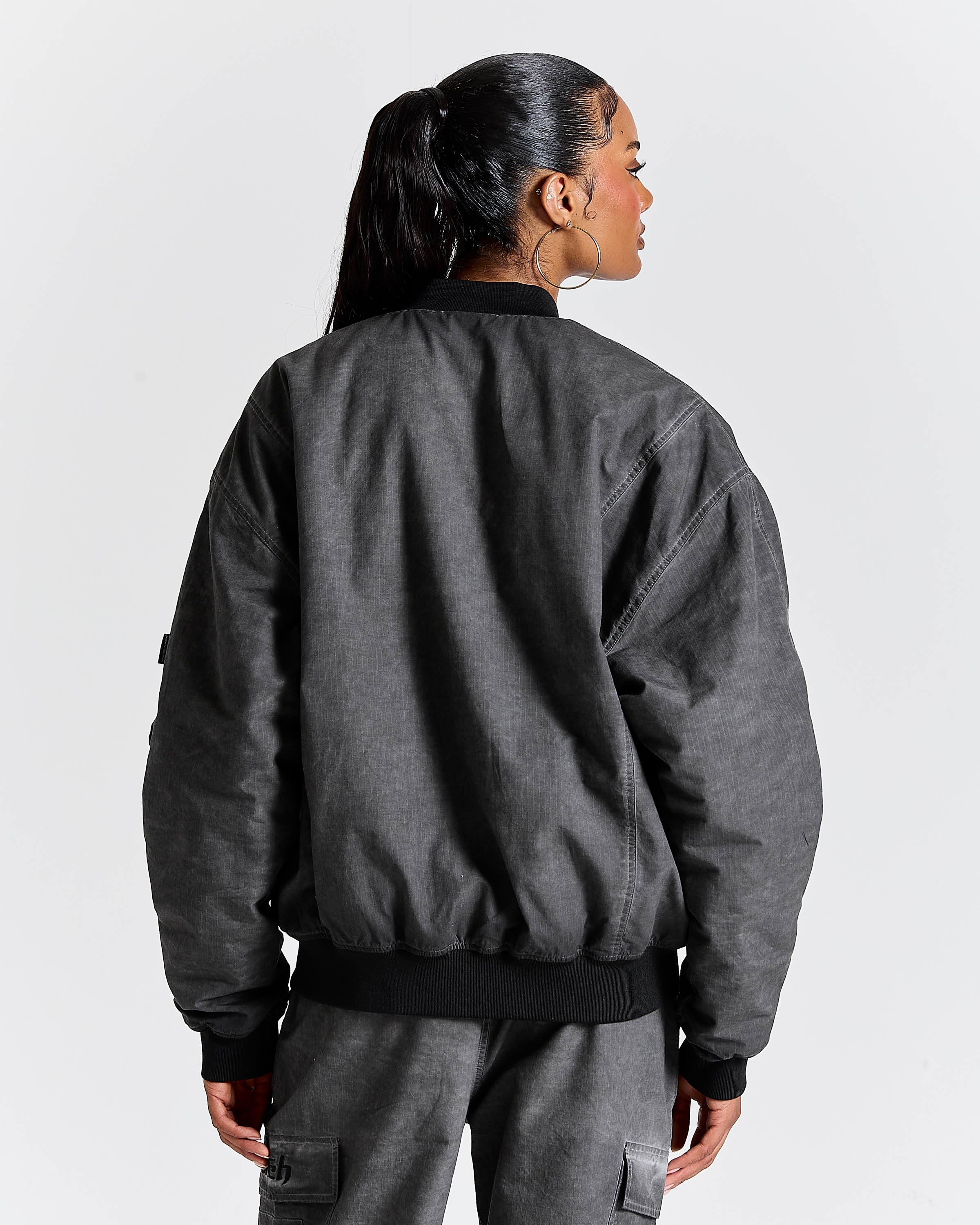 Person wearing a gray bomber jacket and pants on a white background