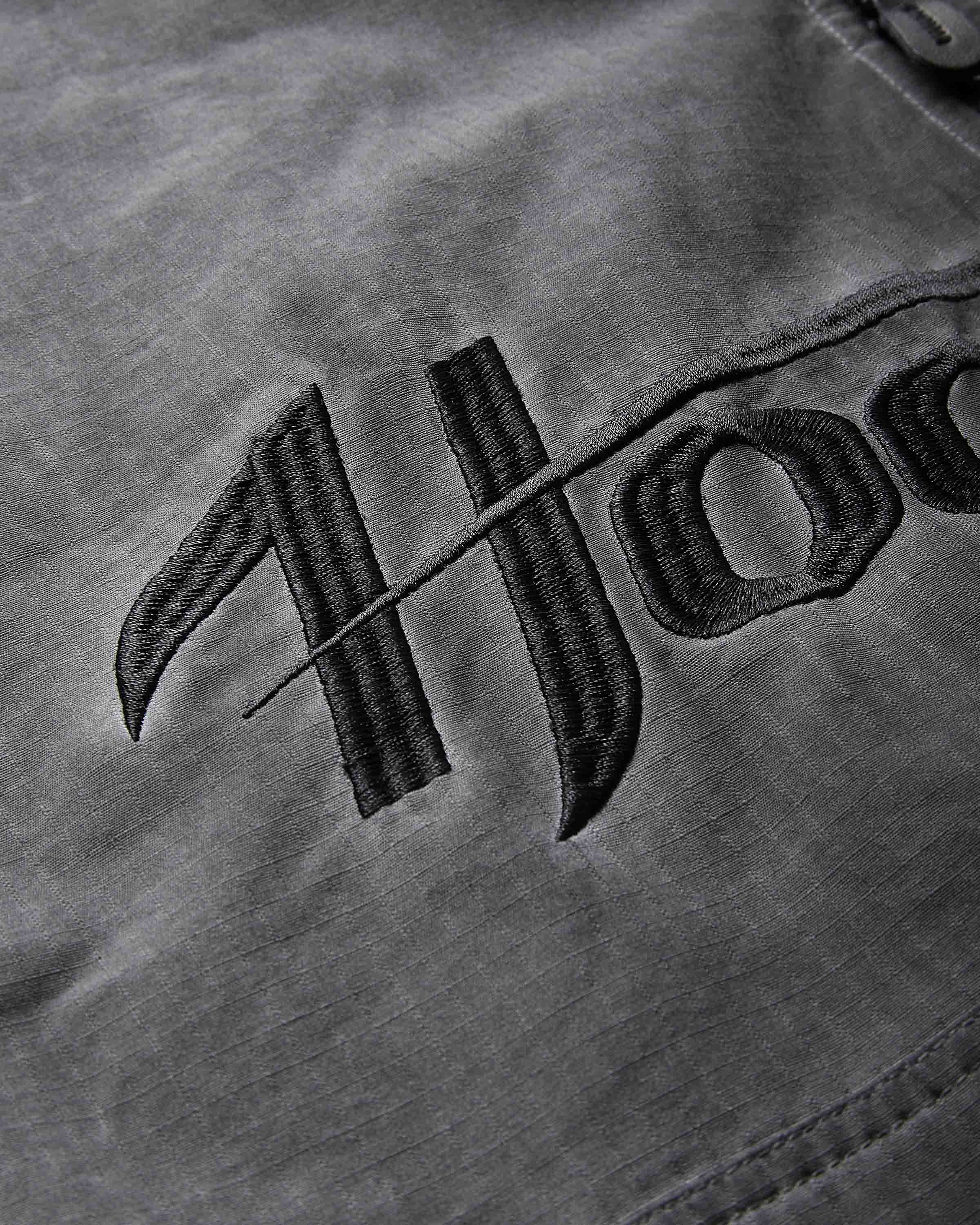 Close-up of a dark gray fabric surface with black embroidered Gothic-style lettering.