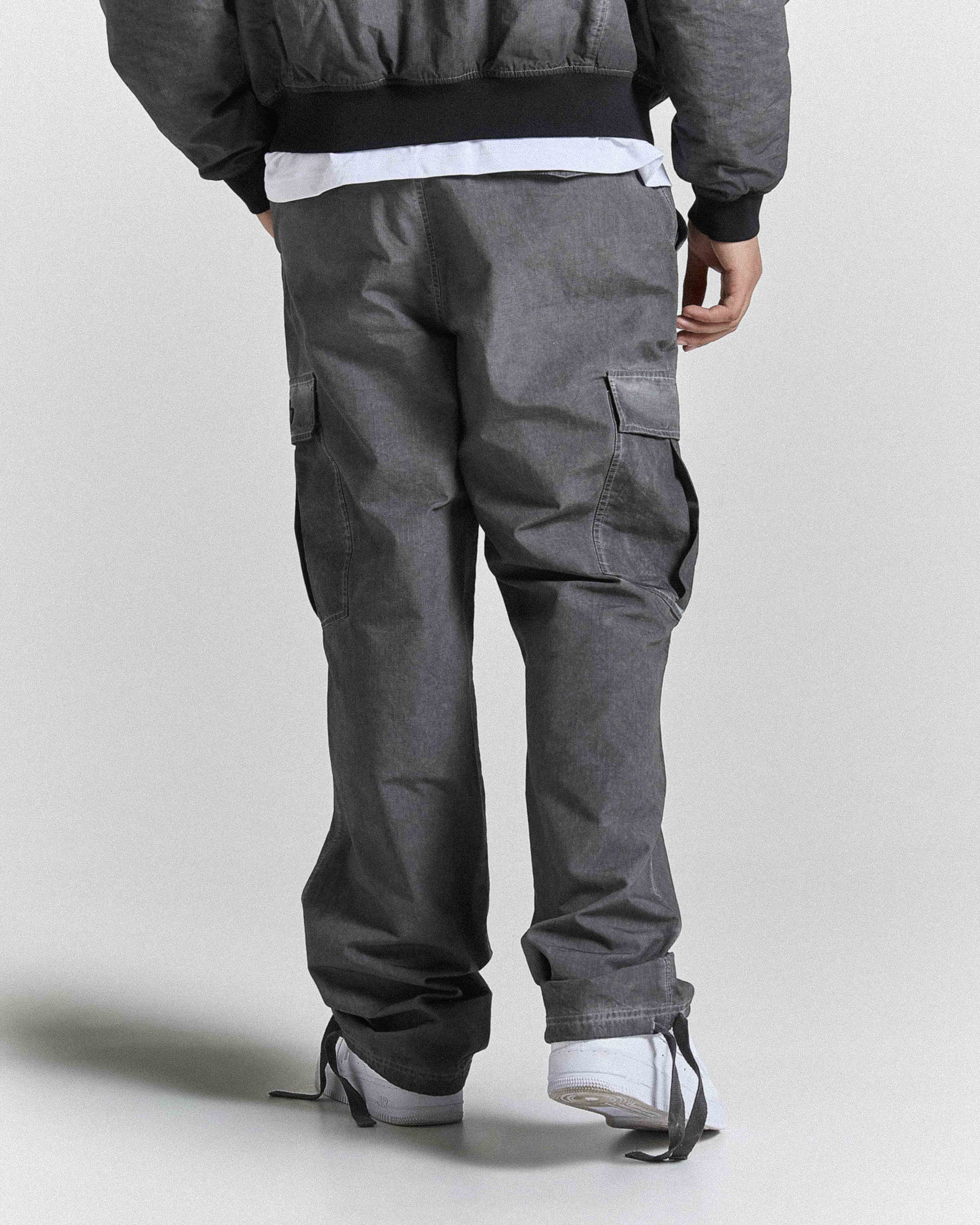 Person wearing gray cargo pants on a plain background