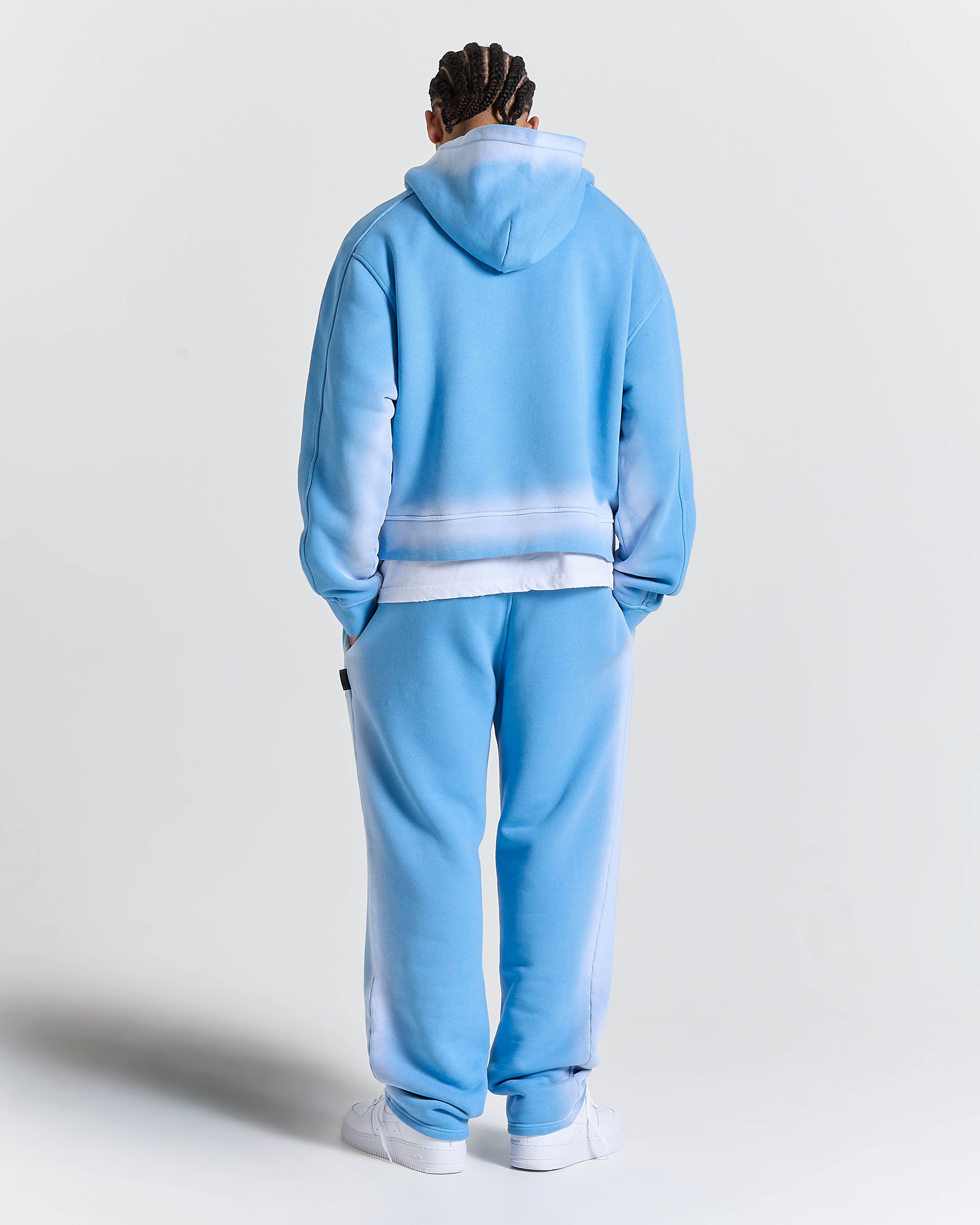 Person wearing a light blue tracksuit with white accents on a plain background