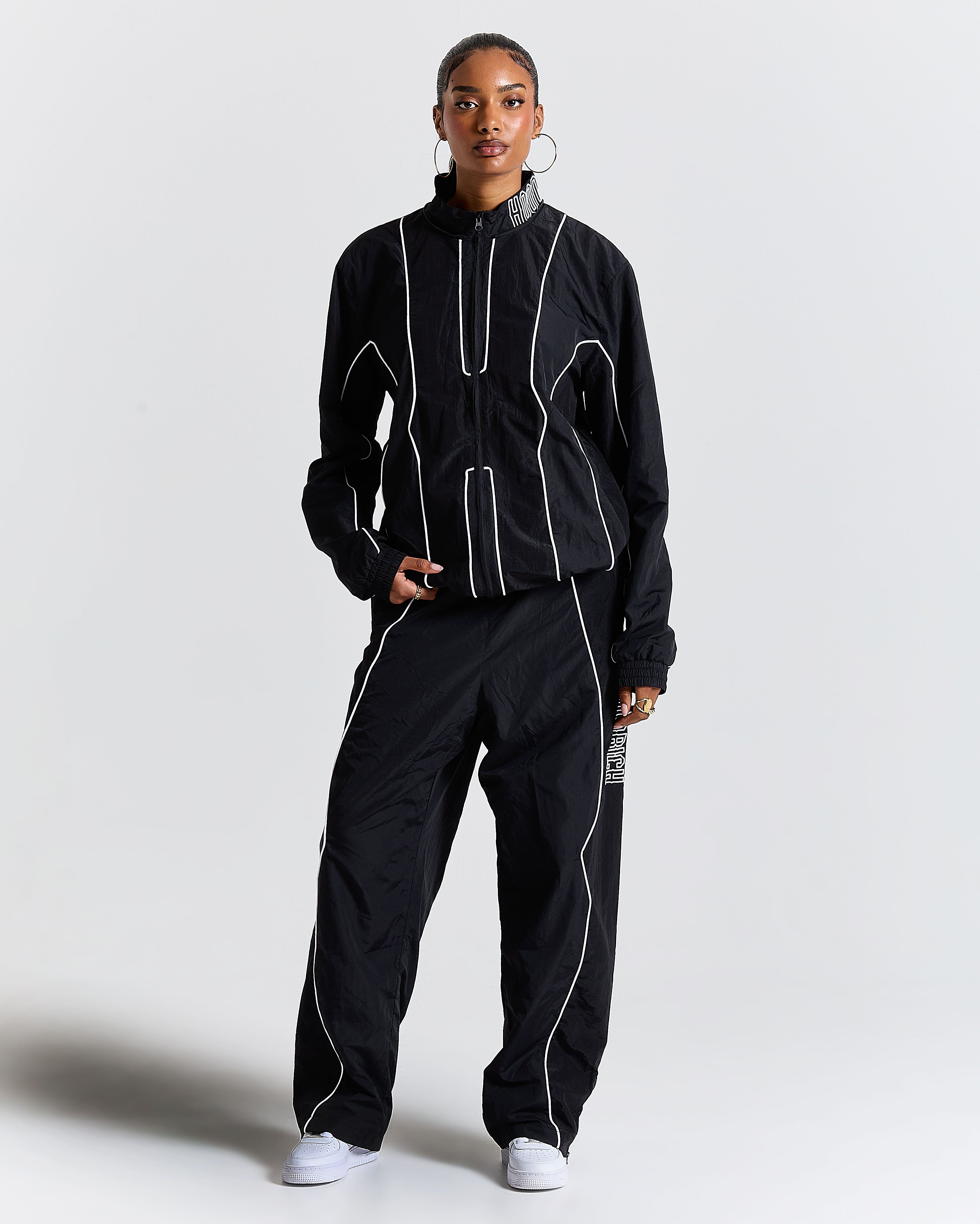 Person wearing a black tracksuit with white accents on a light gray background
