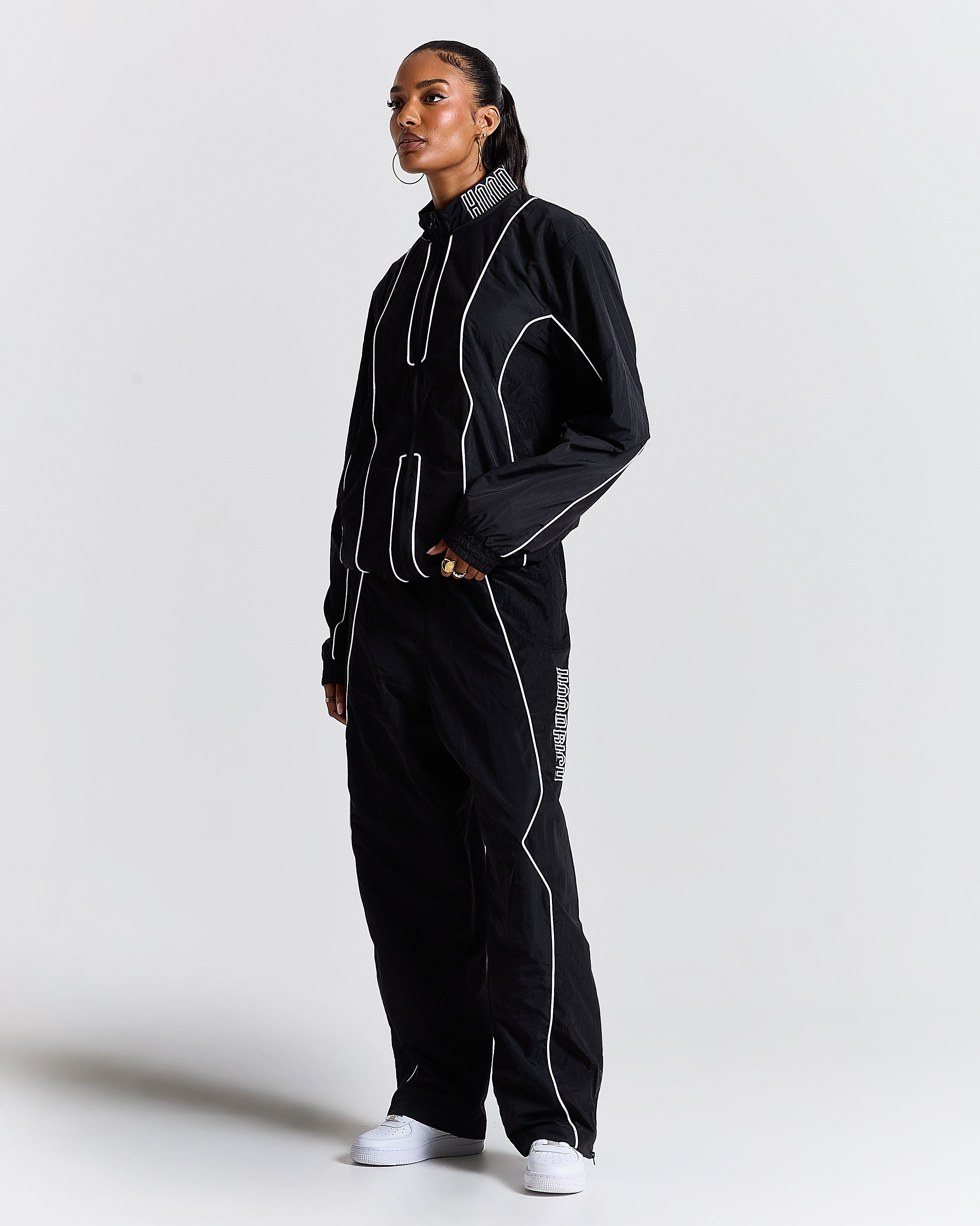 Person wearing a black tracksuit with white accents on a light gray background