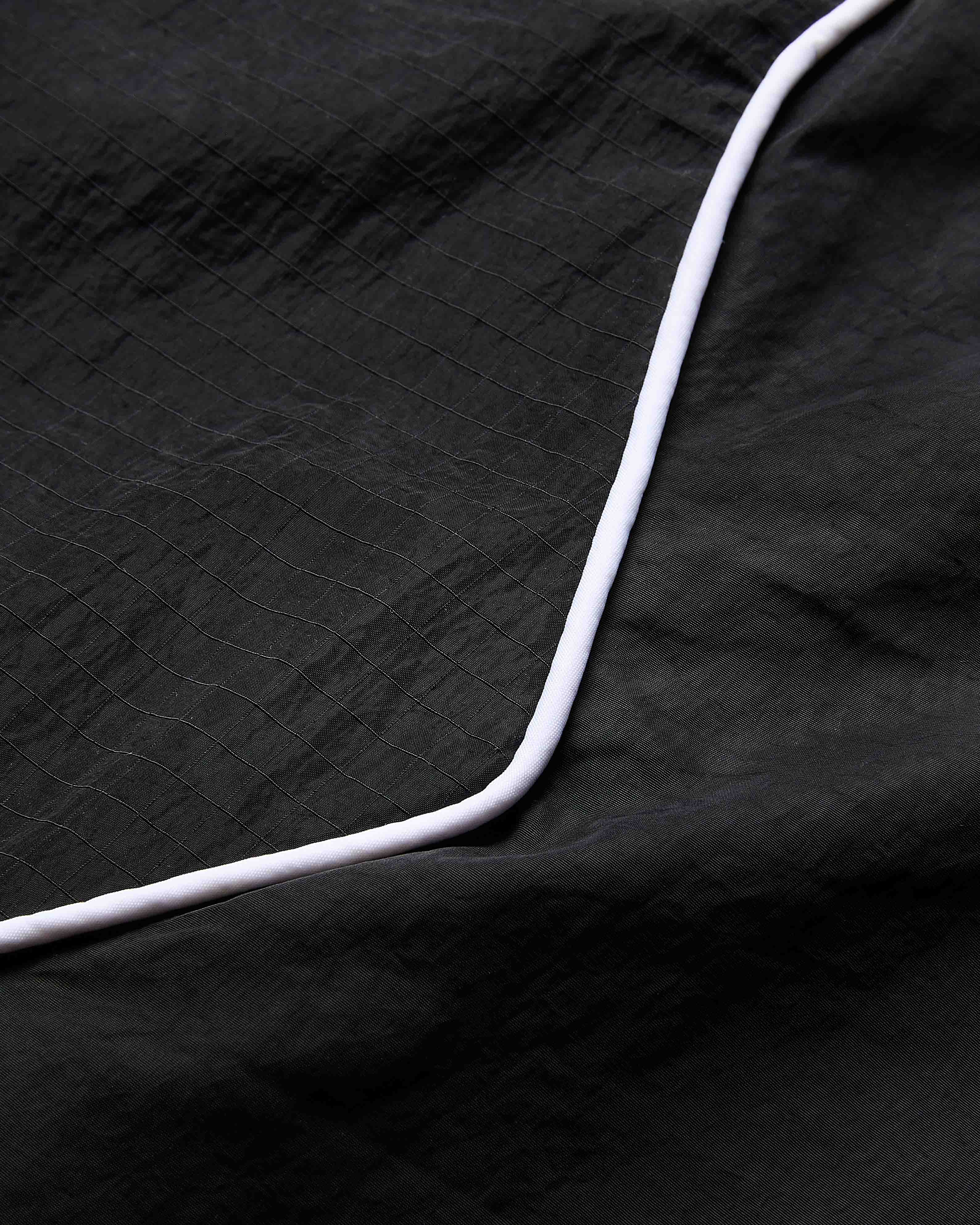Close-up of a black textured fabric with a white edge