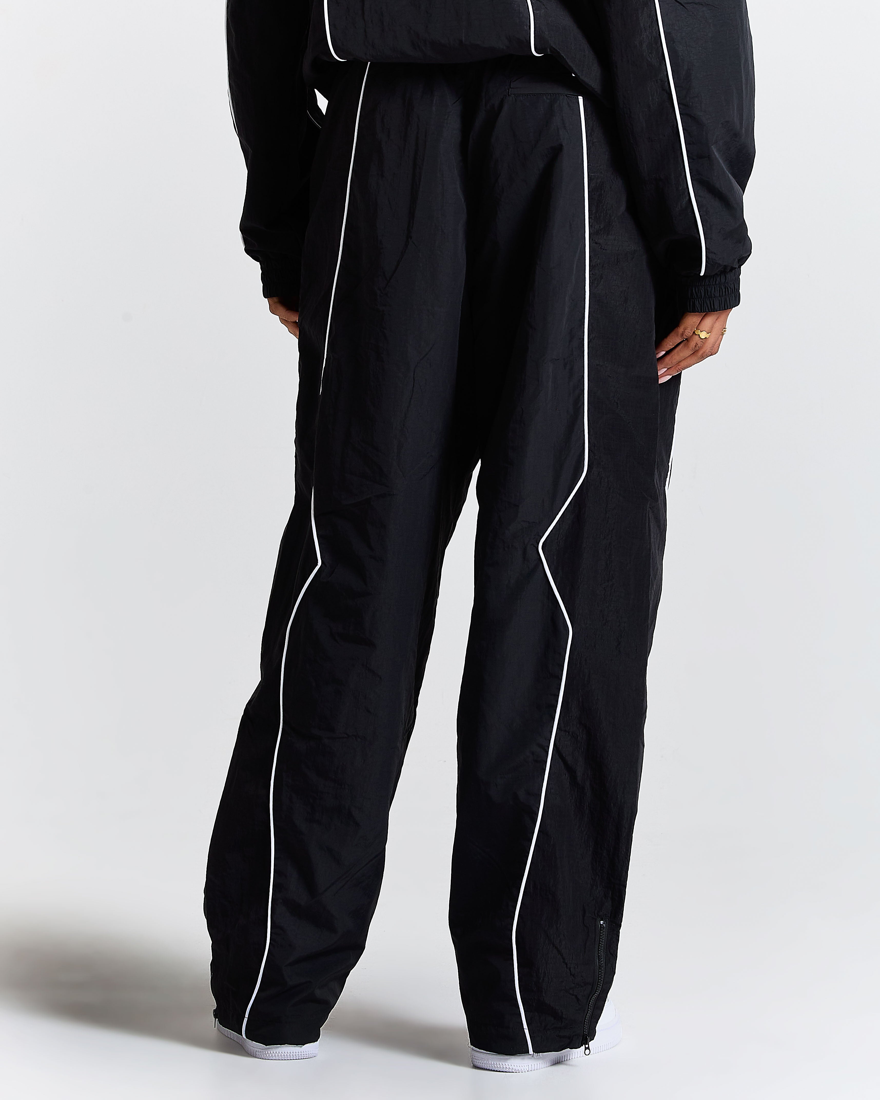 Black tracksuit with white piping on a plain background