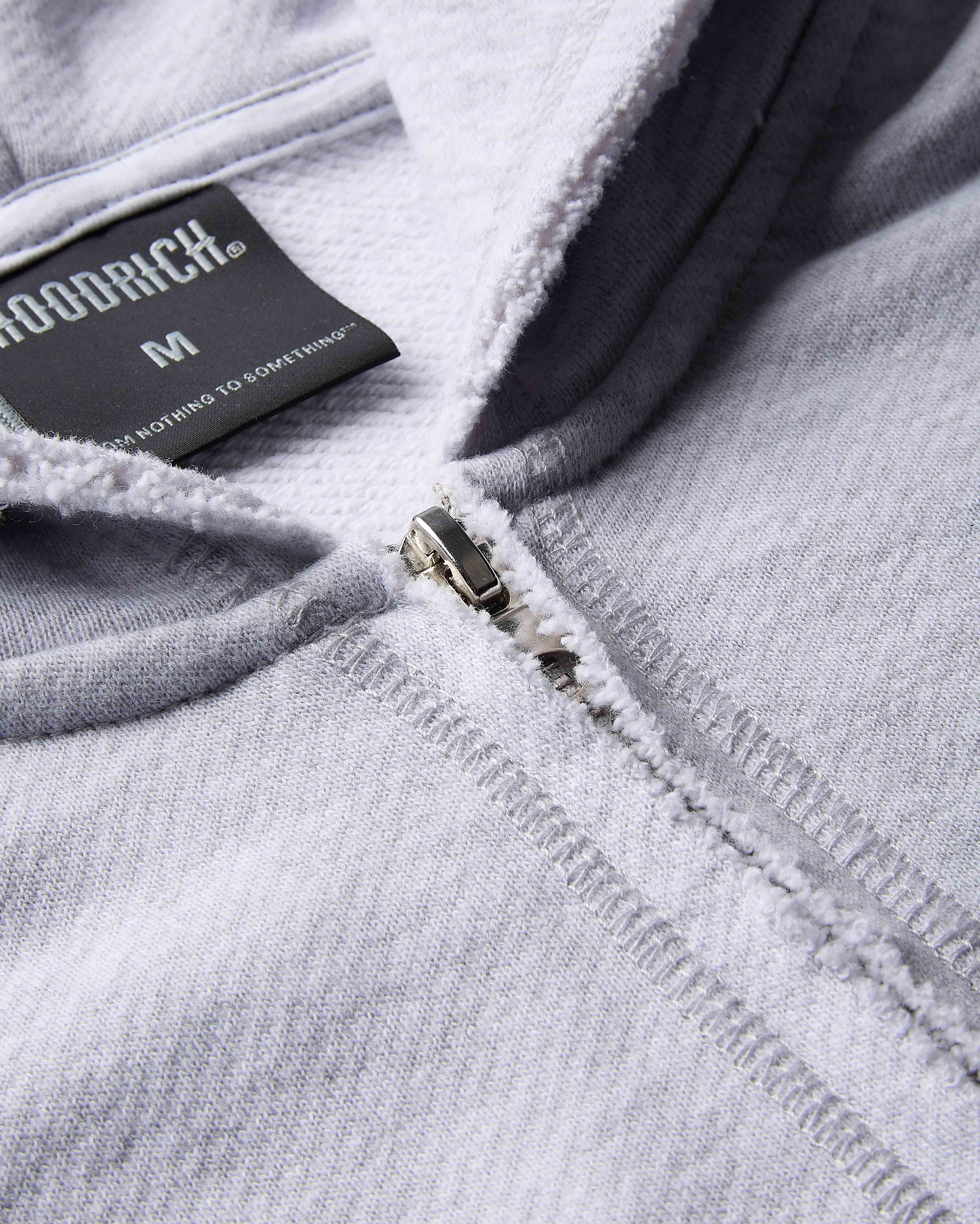 Close-up of a gray hoodie with a brand label on the zipper area.
