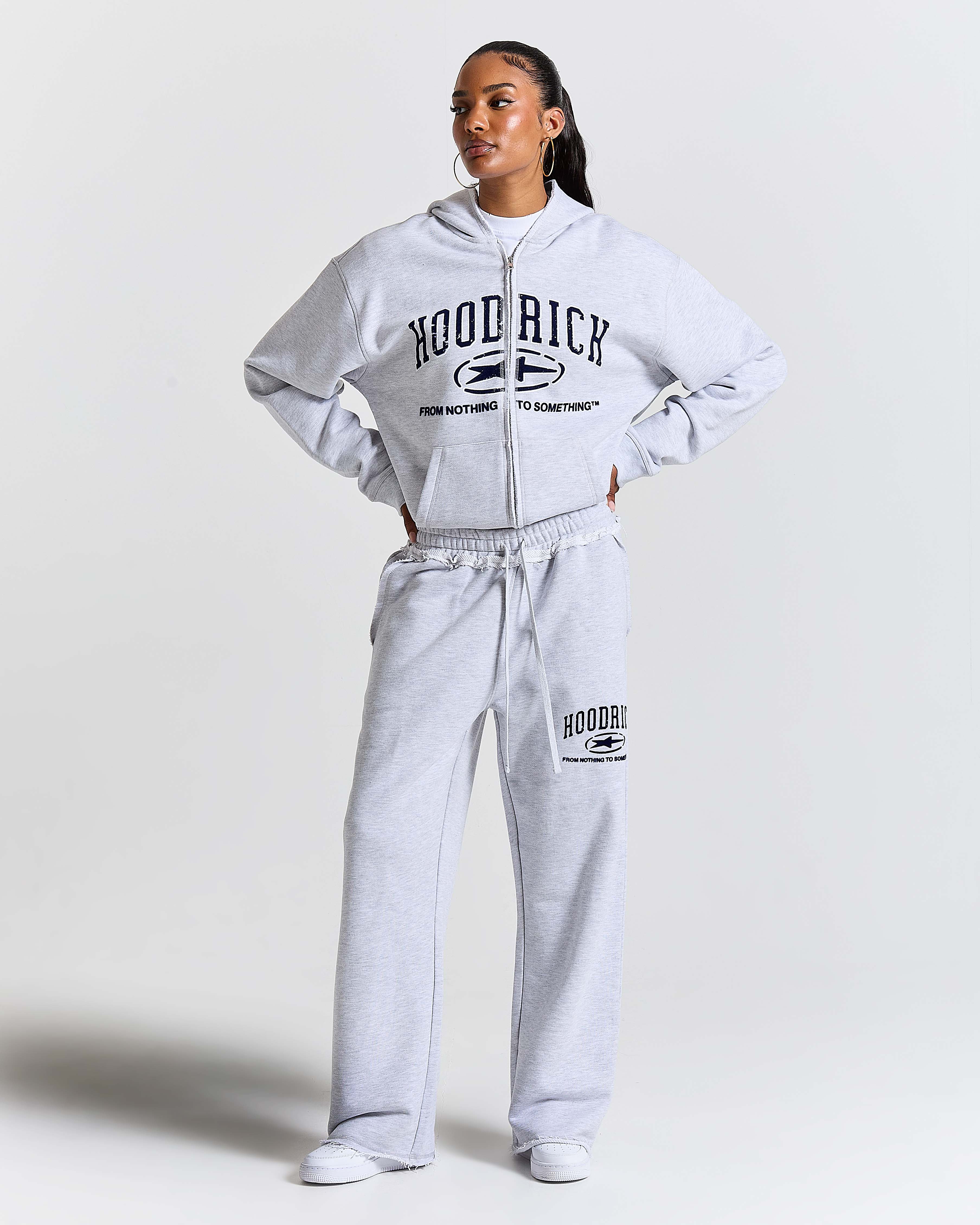 Person wearing a gray 'Hoodrich' tracksuit on a white background