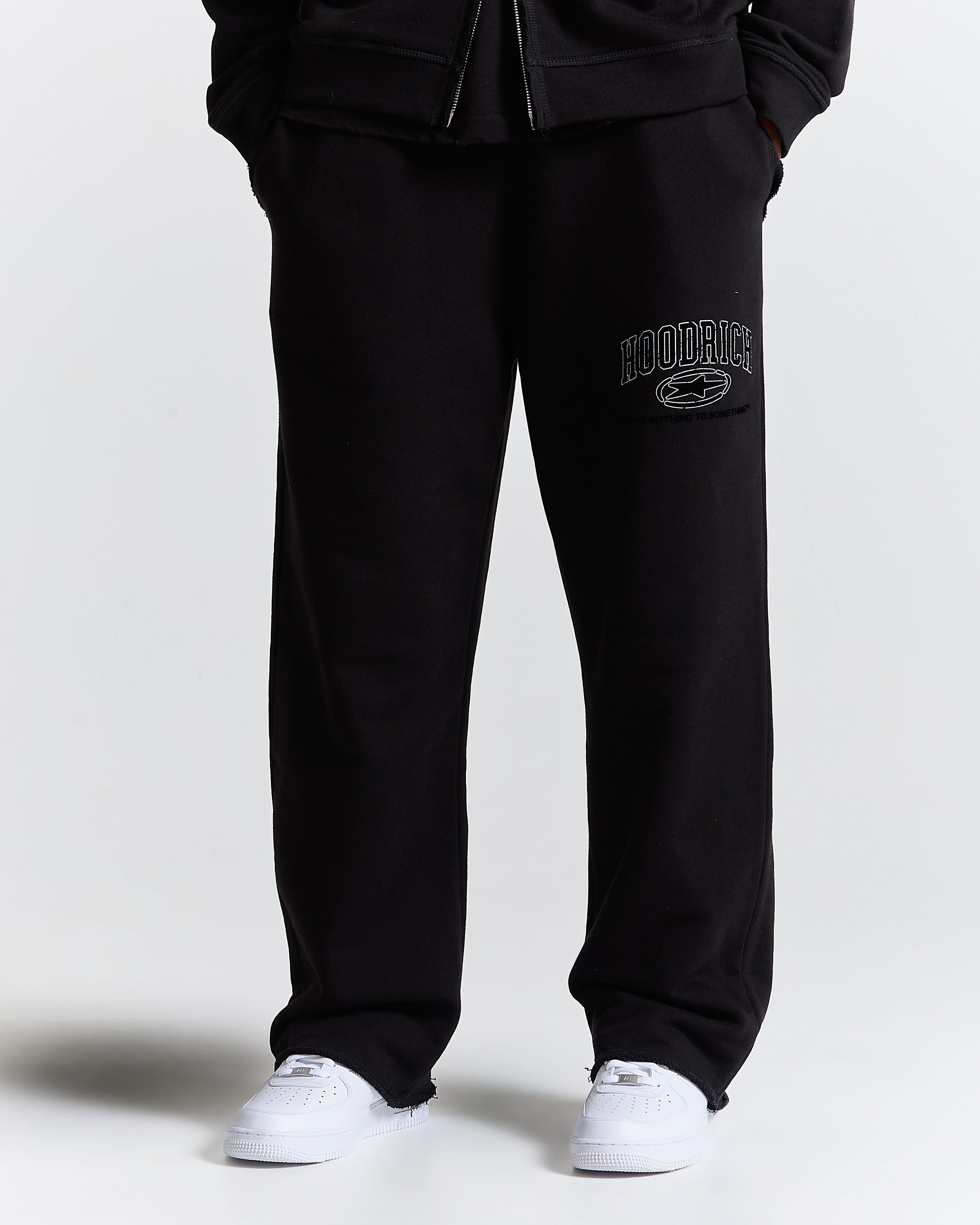 Black sweatpants with a logo on the left leg against a white background