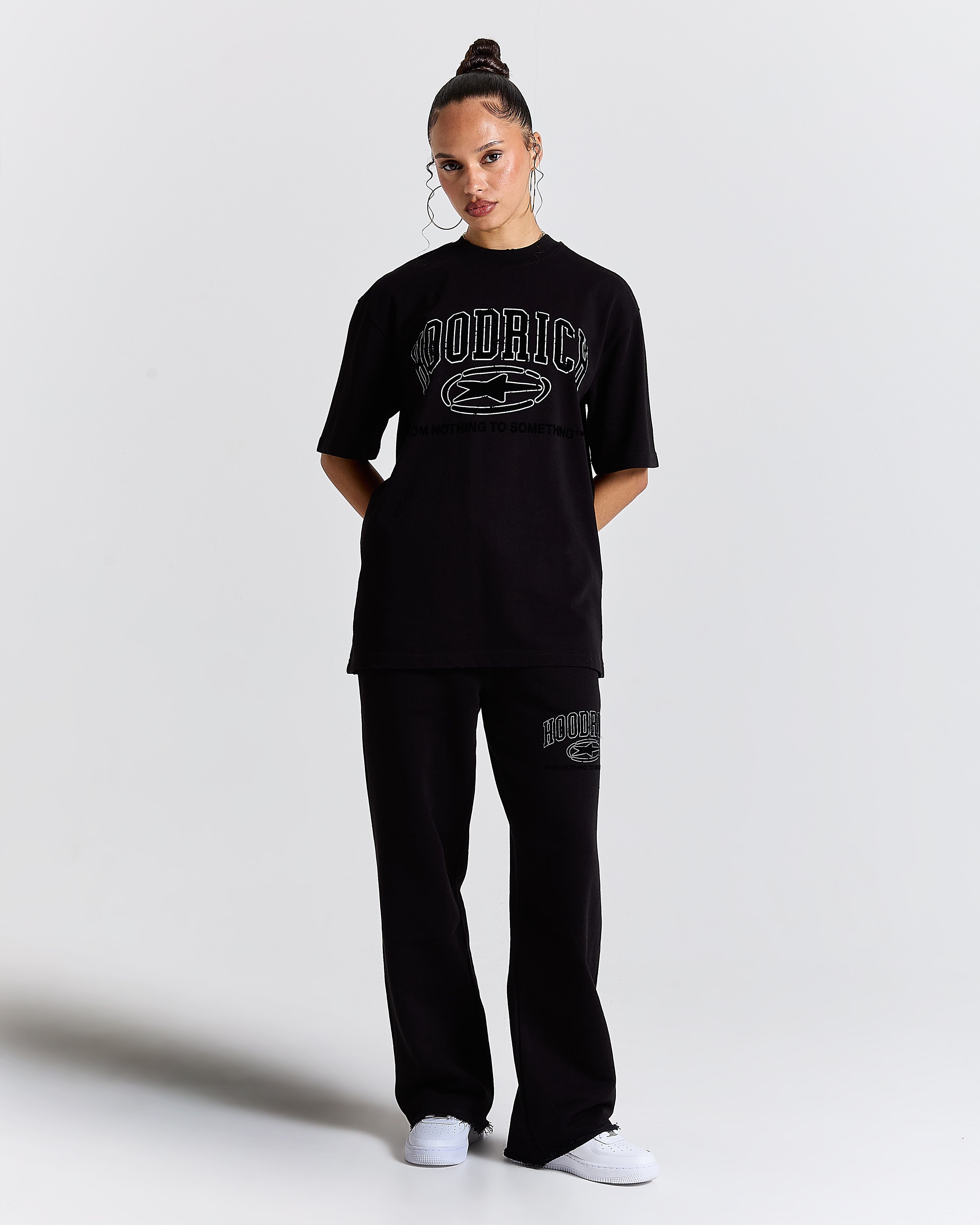Person wearing a black 'Hoodrich' t-shirt and pants on a white background